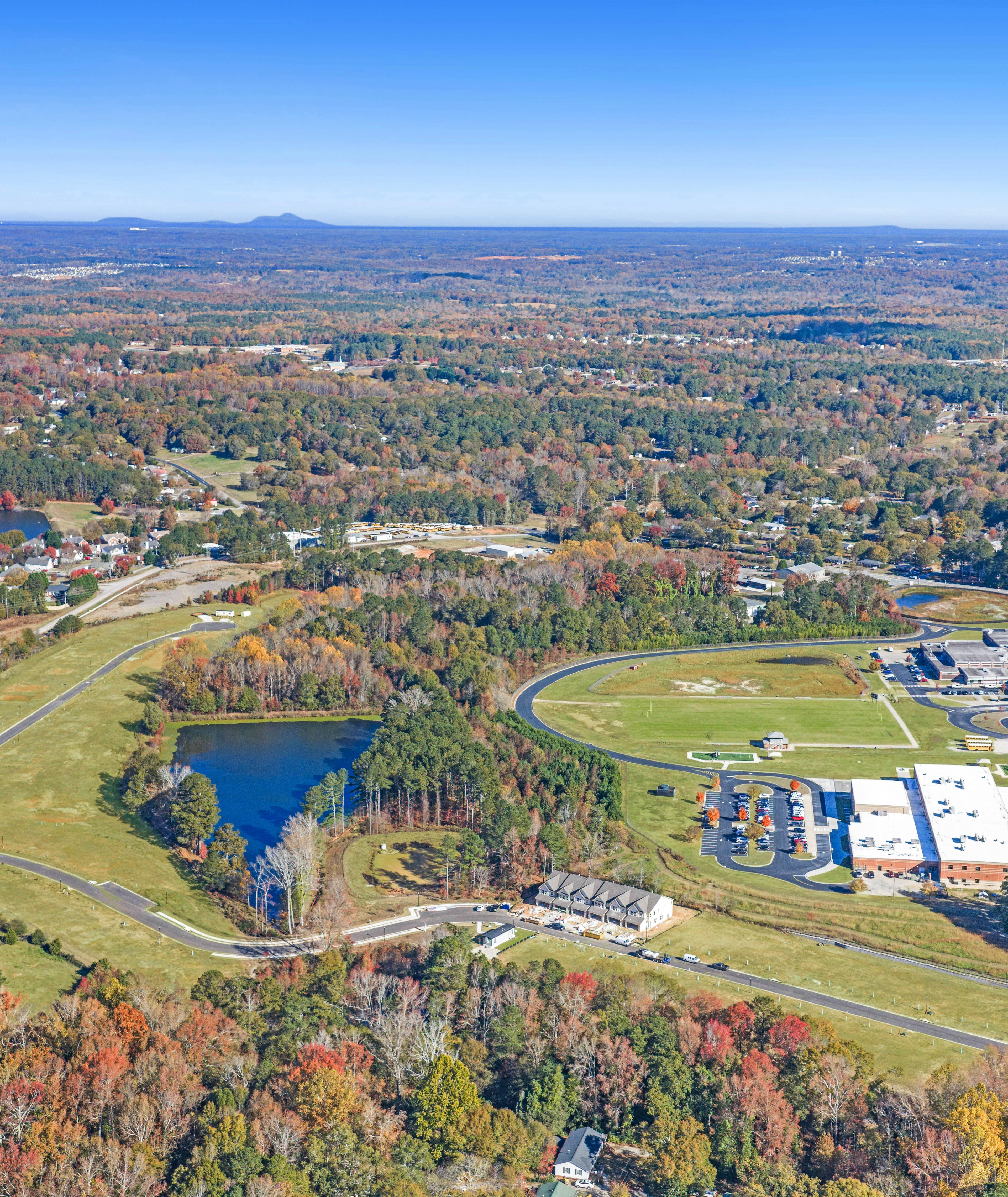 Aerial view of Lake Shore community in Winder GA featuring resort-style pool, clubhouse, lush forest, and serene lakefront