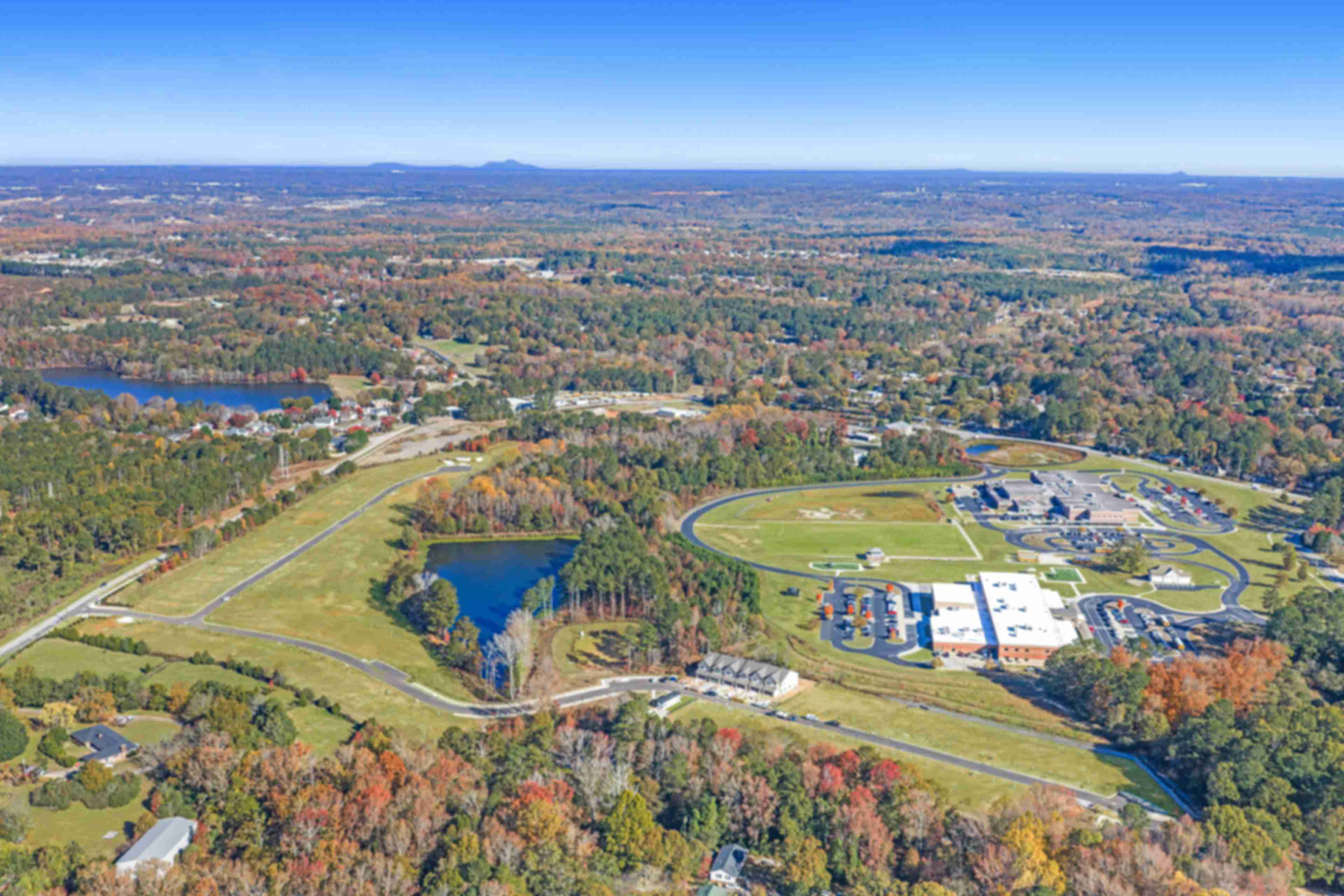 Aerial view of Lake Shore community in Winder GA featuring resort-style pool, clubhouse, lush forest, and serene lakefront