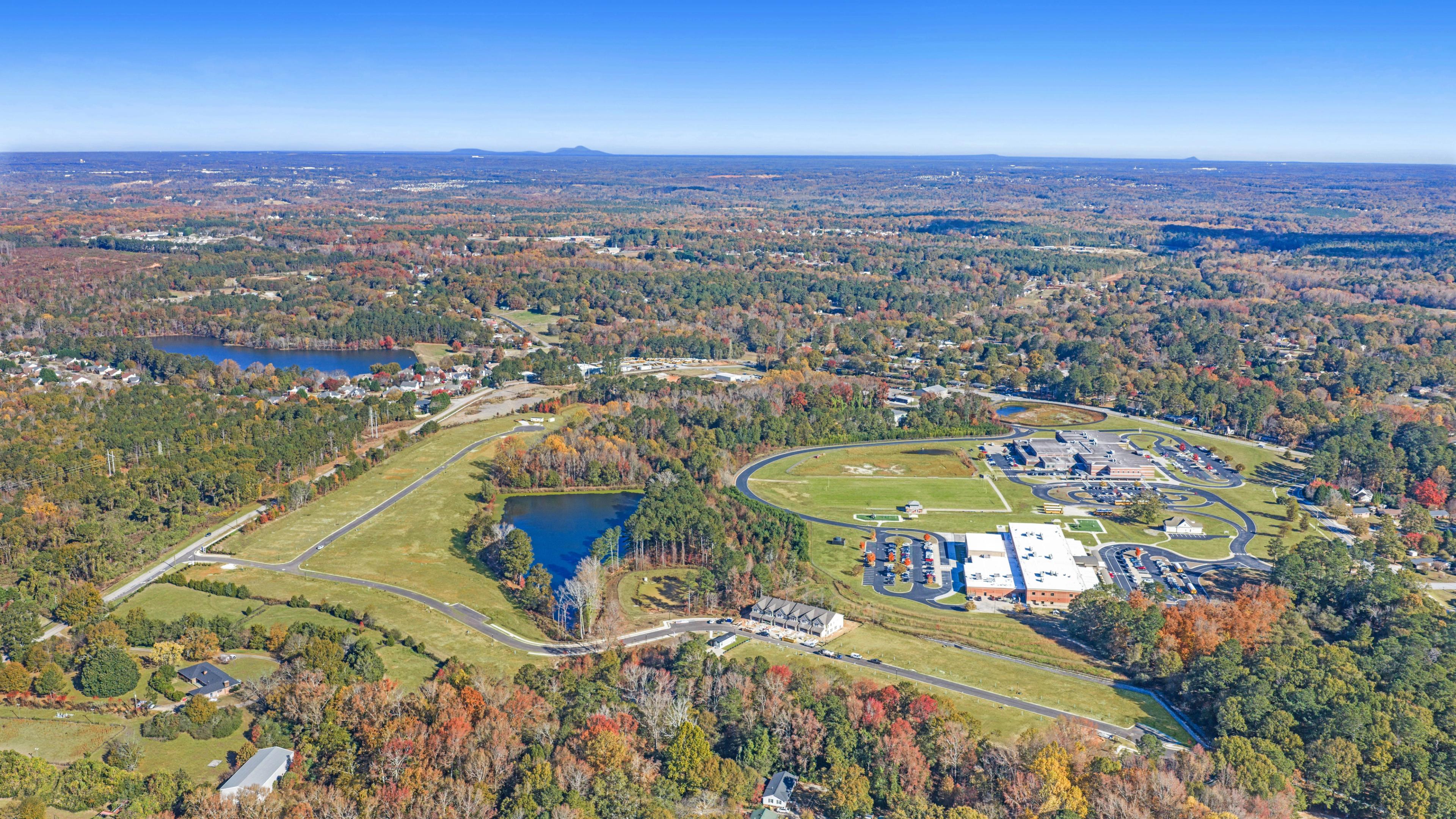 Aerial view of Lake Shore community in Winder GA featuring resort-style pool, clubhouse, lush forest, and serene lakefront