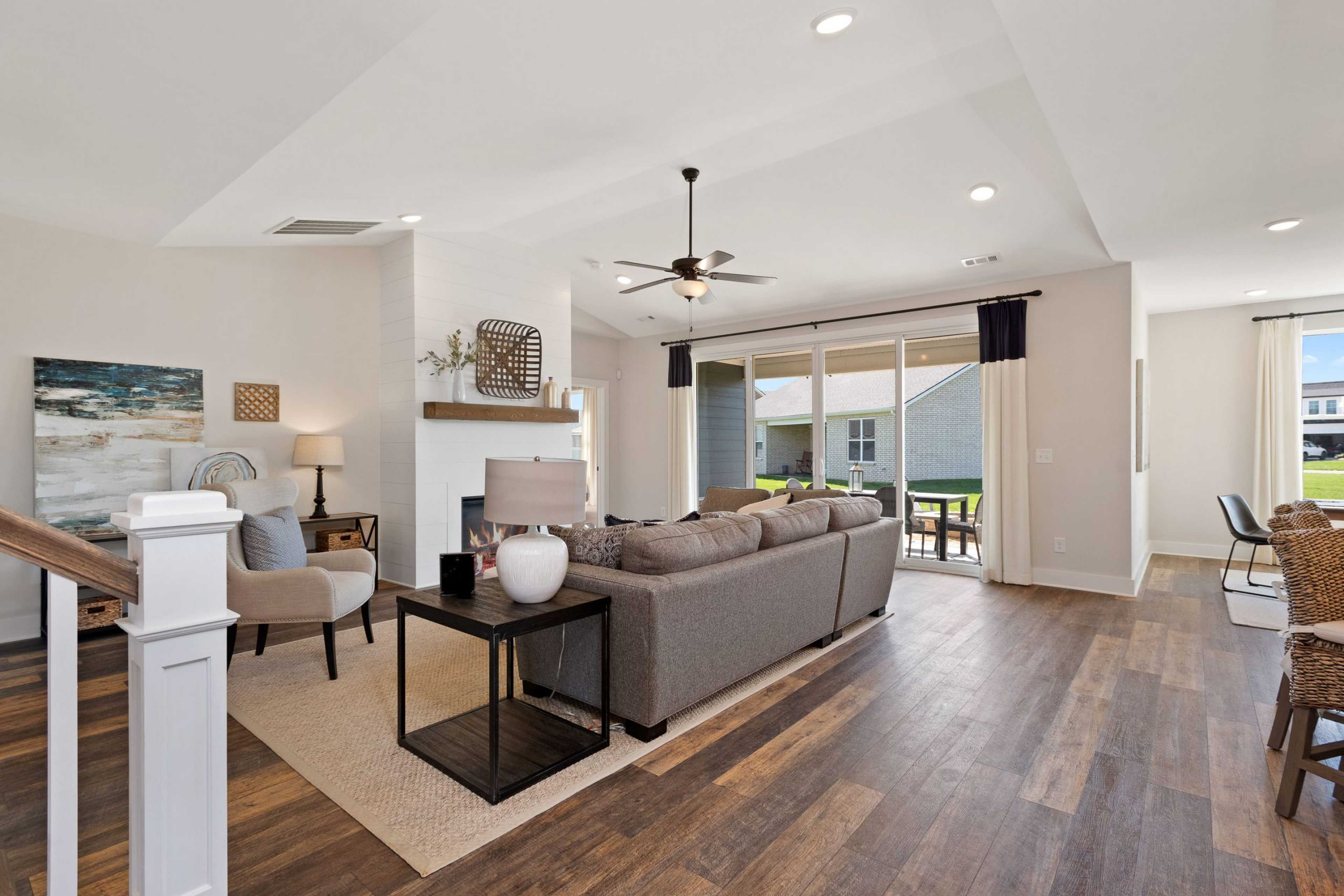 Open-concept living room at Rivers Edge in Murfreesboro TN featuring hardwood floors, gray sectional sofa, fireplace, and sliding doors to patio