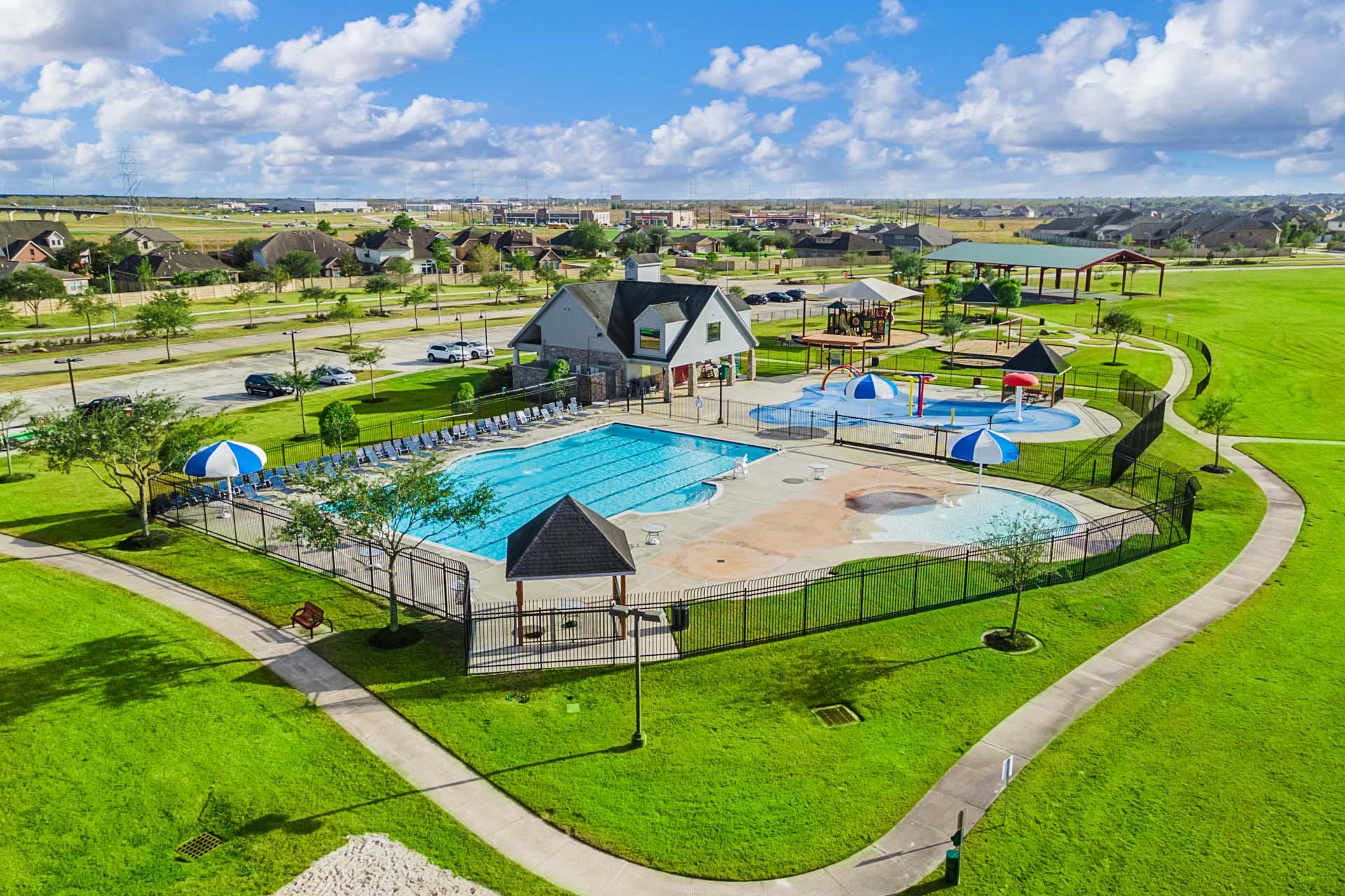 Resort-style pool and clubhouse at Sierra Vista in Rosharon Texas by Davidson Homes with lounge chairs kids splash pad and green lawns