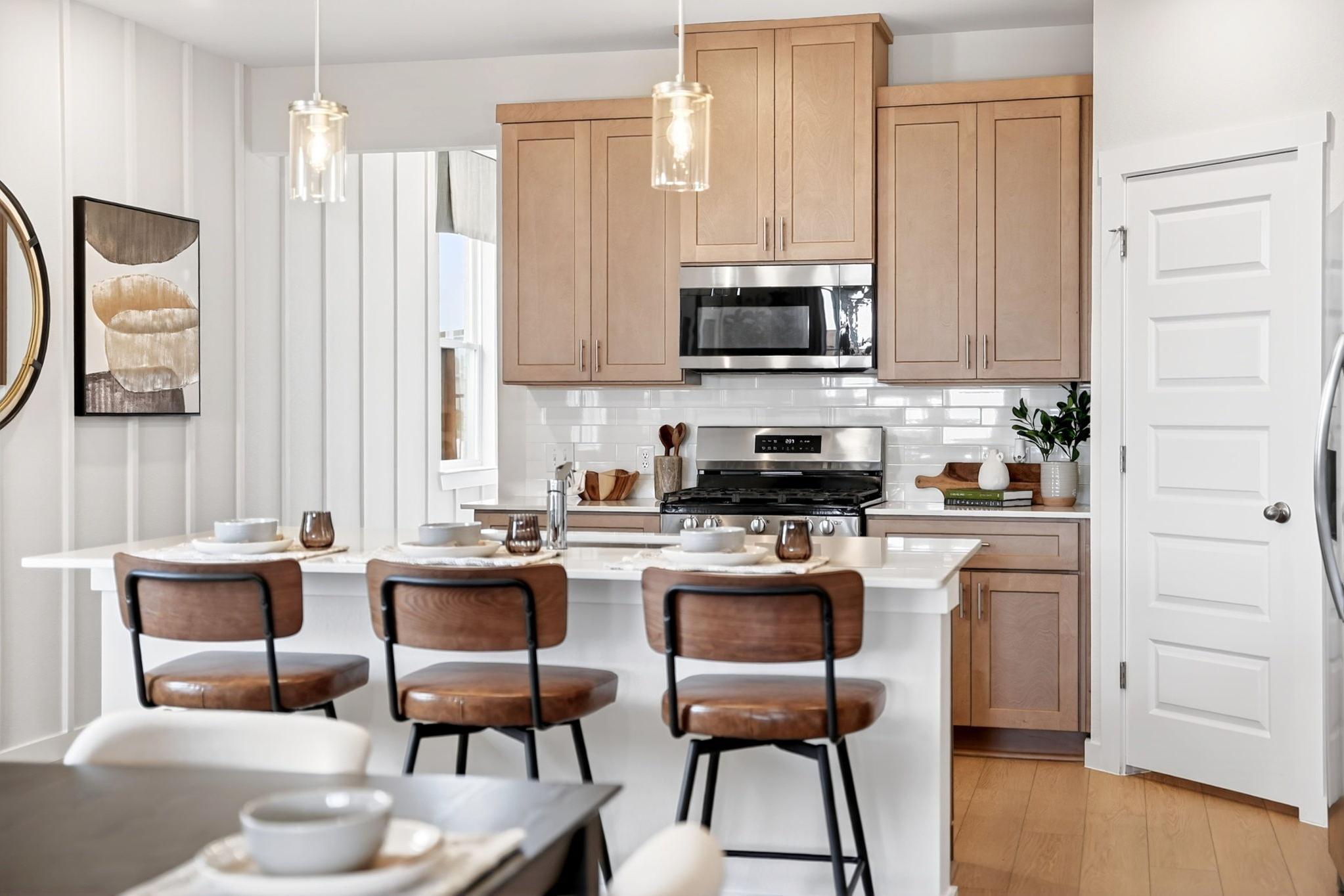 Modern kitchen with light oak cabinets, white quartz island, subway tile backsplash in Heartland Texas home by Davidson Homes