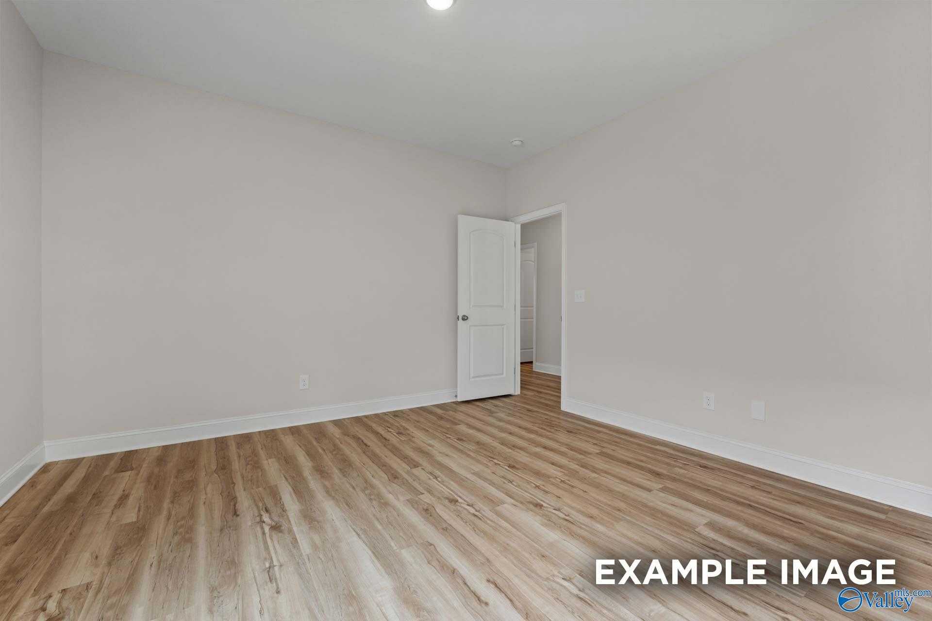 Spacious bedroom with hardwood floors, neutral walls, and interior doorway in Davidson Homes The Butler, Toney, Alabama