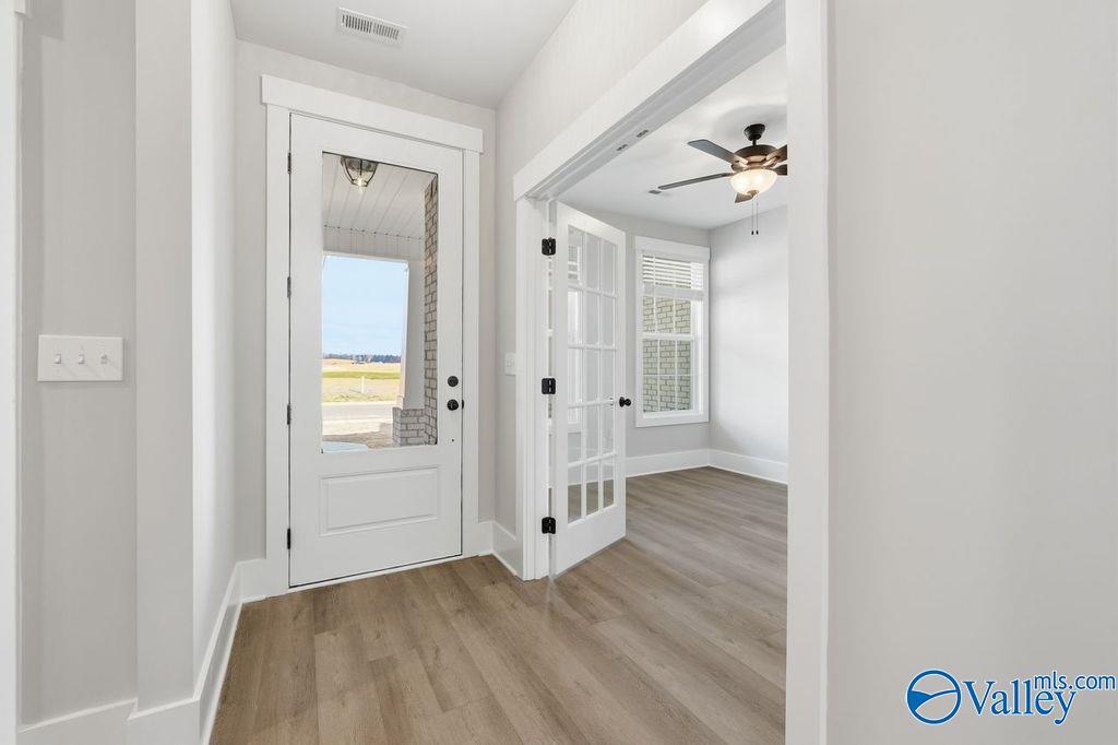 Glass-paneled French doors opening to scenic field view with ceiling fan in Davidson Homes The Rockford, Hartselle, AL