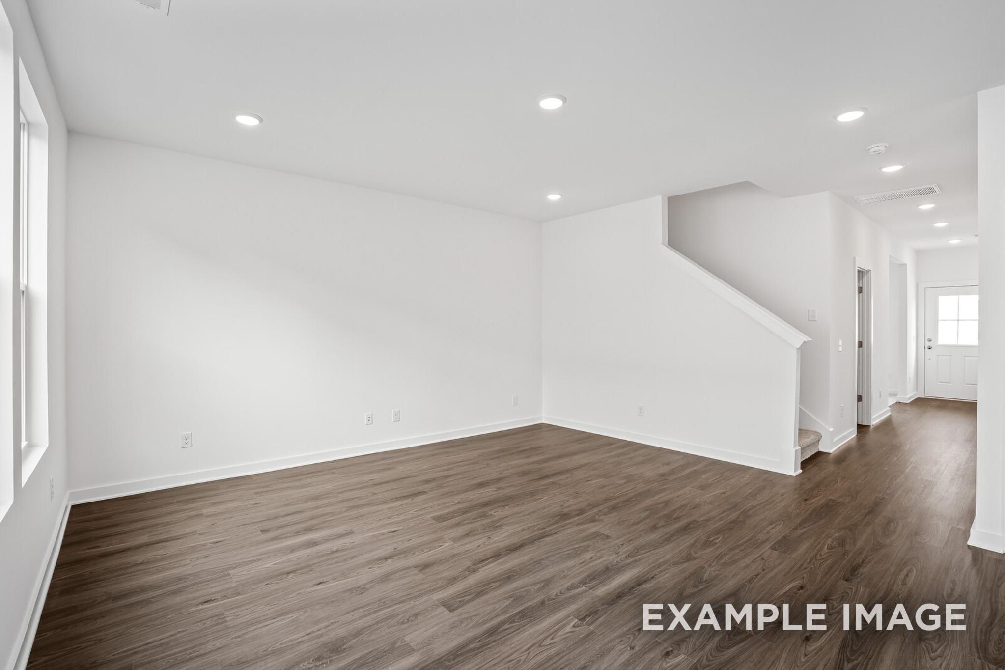 Spacious open foyer in The Logan C two-story home by Davidson Homes, featuring hardwood floors, white walls, and central staircase