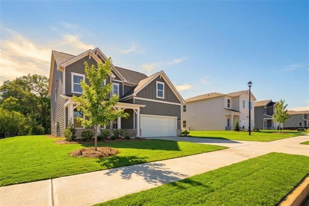 Two-story gray Hickory B home with two-car garage, front porch, and landscaped yard in Cedar Farms, Winder, Georgia