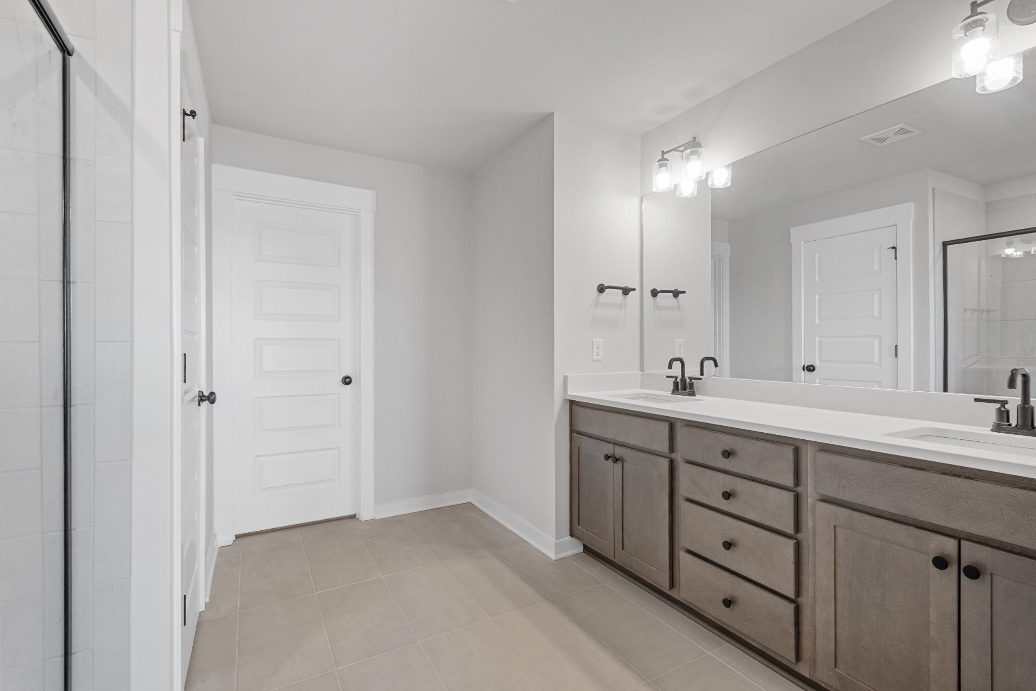 Modern master bathroom featuring double vanity, frameless glass shower, and linen closet in Davidson Homes The Willow B, White House, TN