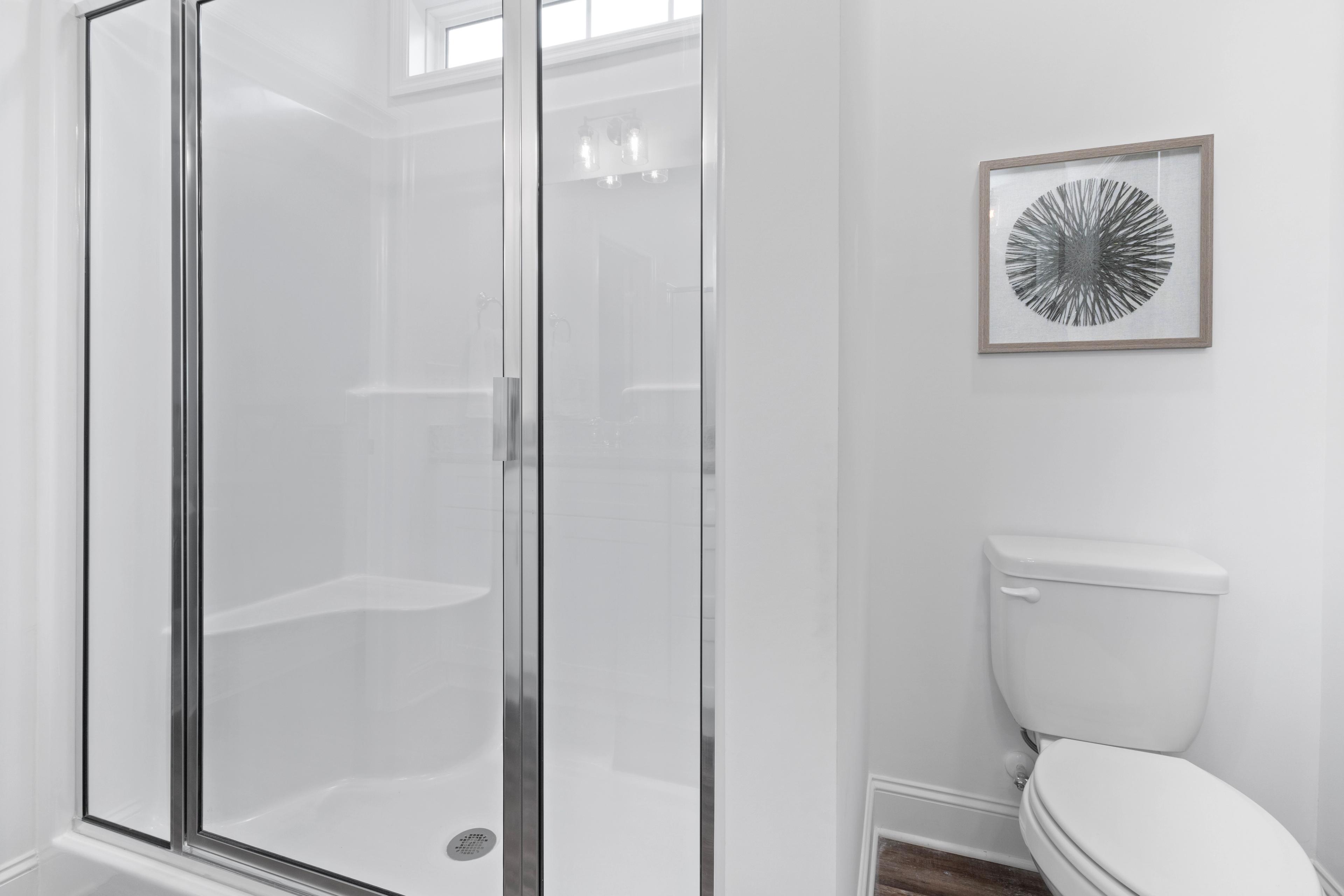 Modern master bathroom in The Cumberland B featuring frameless glass shower, built-in bench, and white toilet