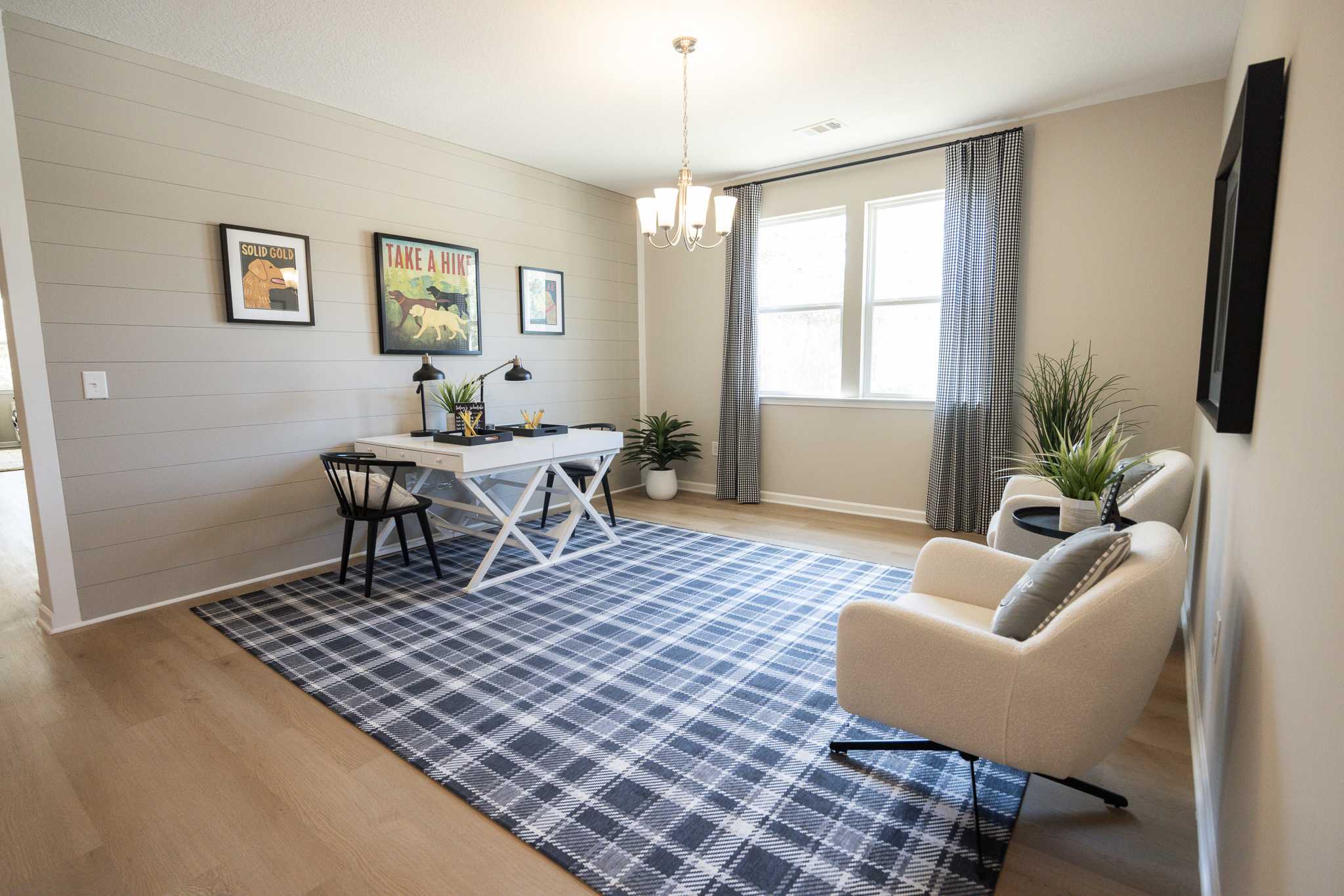Cozy home office in Silver Oak Cusseta Alabama by Evermore Homes with white desk, plaid rug, shiplap walls, and armchairs