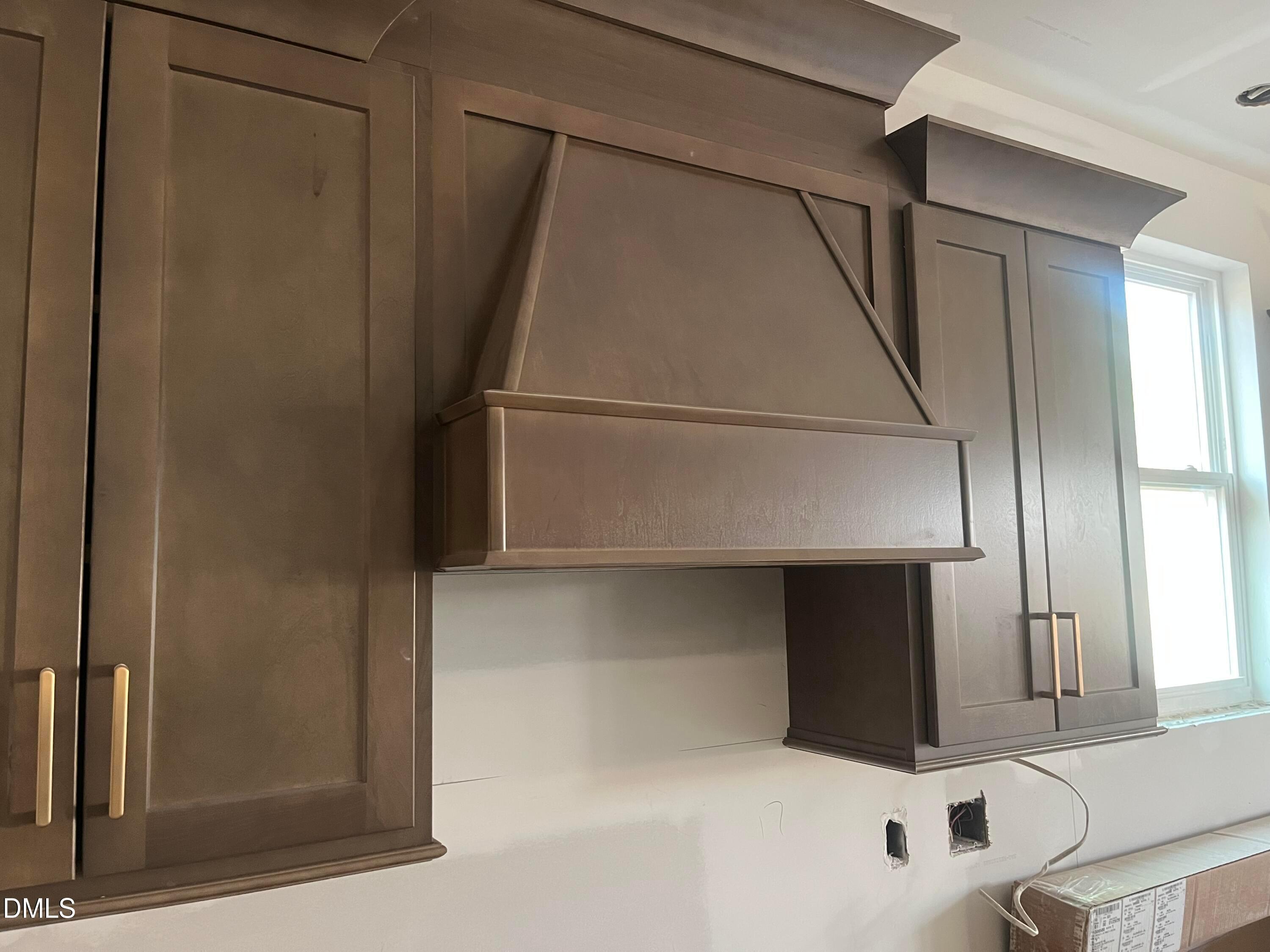 Elegant shaker-style wooden kitchen cabinets and oversized range hood in Davidson Homes The Ashport G, Wake Forest, NC