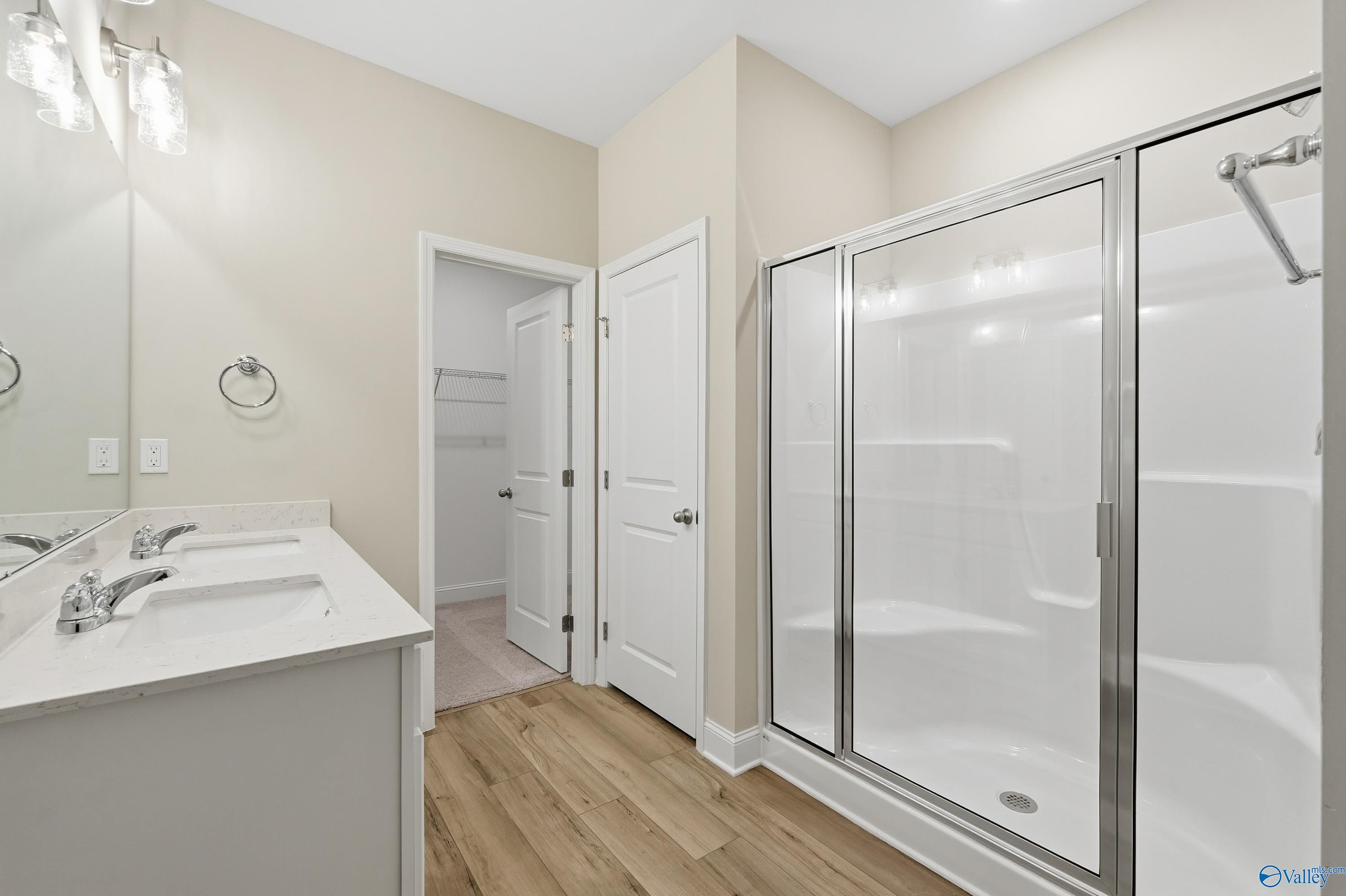 Modern master bathroom with double vanity, frameless glass shower, and wood flooring in Davidson Homes The Franklin C, New Market, Alabama