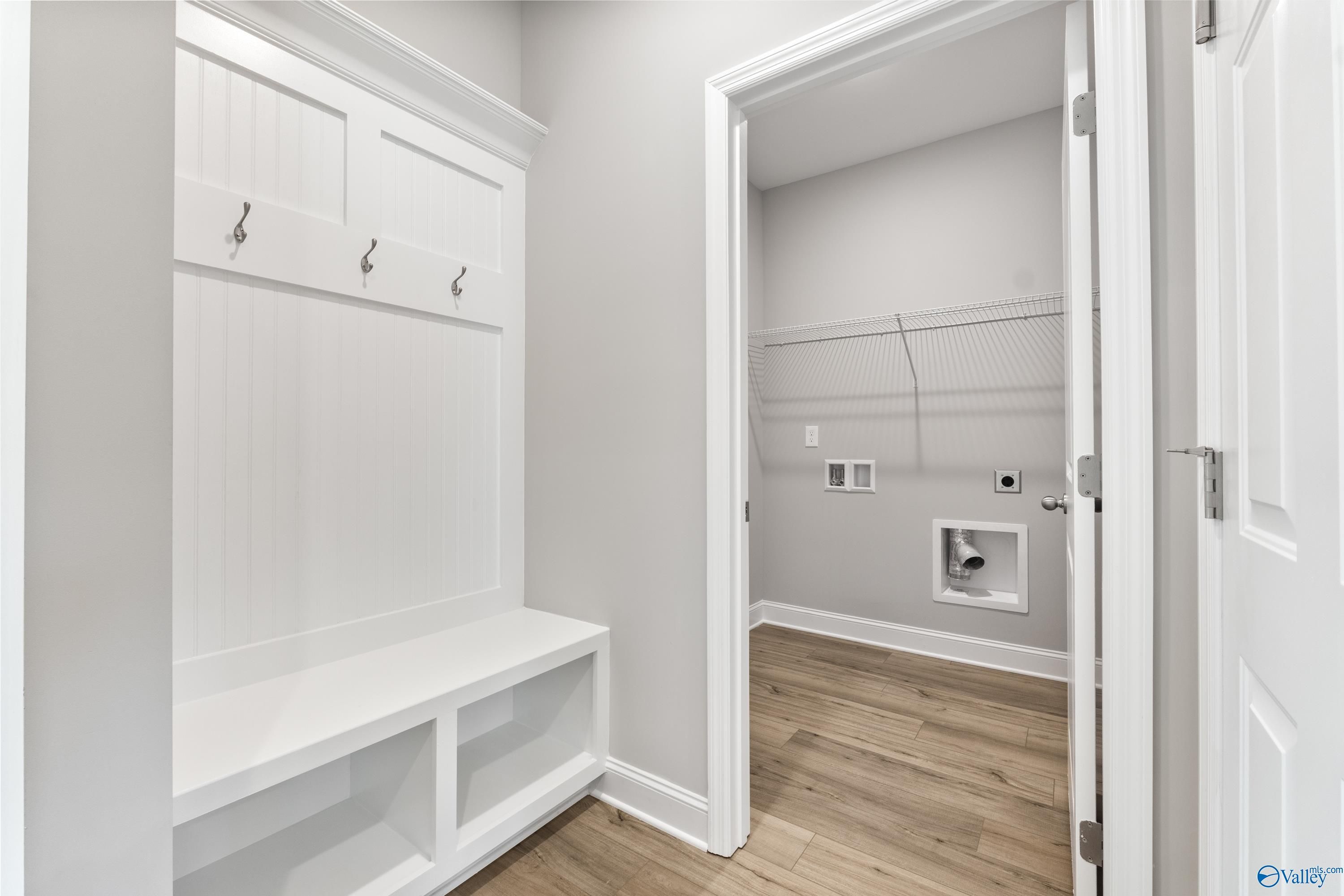 Functional mudroom with white shiplap bench, coat hooks, and laundry utilities in Davidson Homes The Franklin C, Huntsville, Alabama