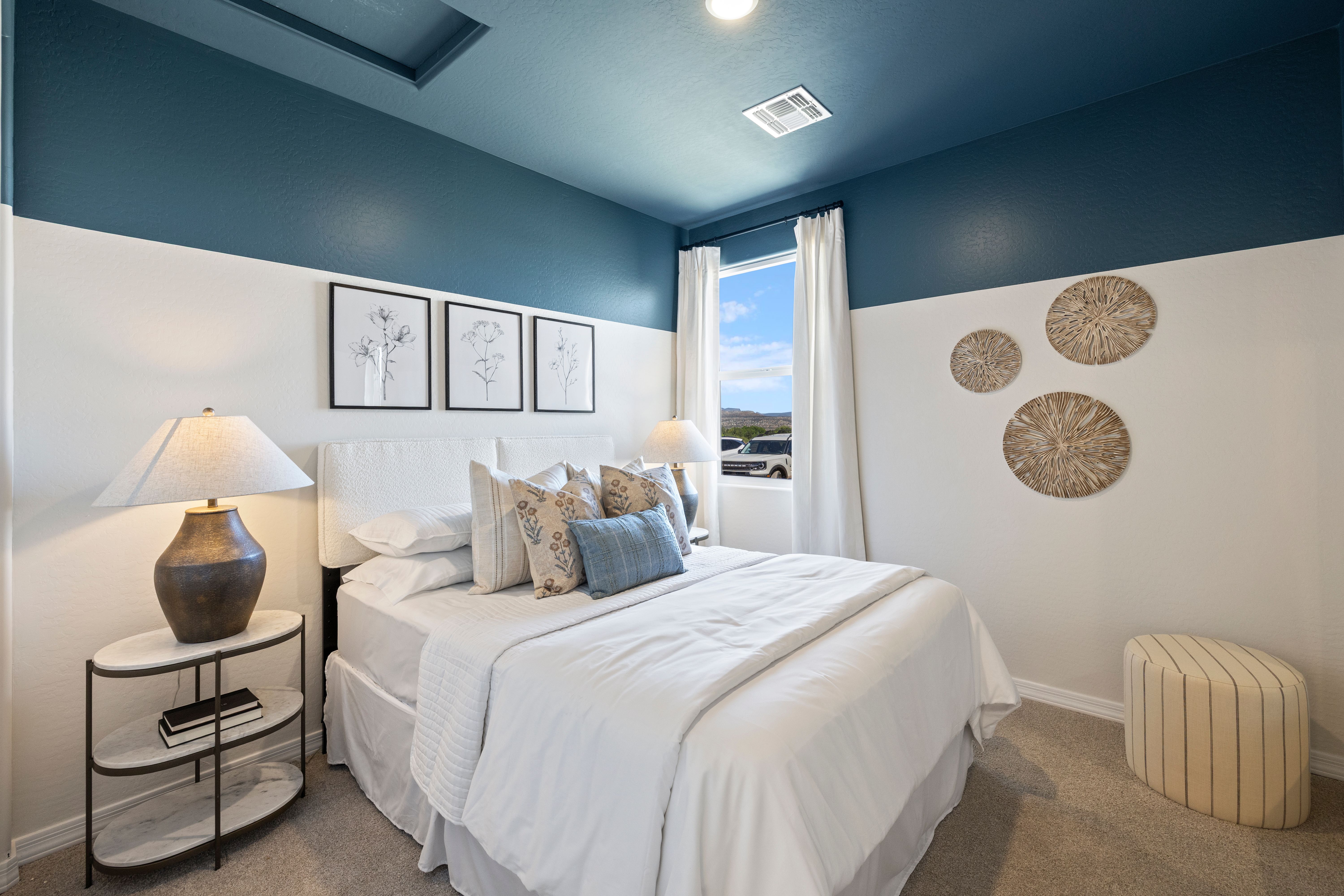 Spacious master bedroom at Vineyards at Cottonwood in Cottonwood AZ with navy accent wall, king bed, woven wall art, and botanical prints
