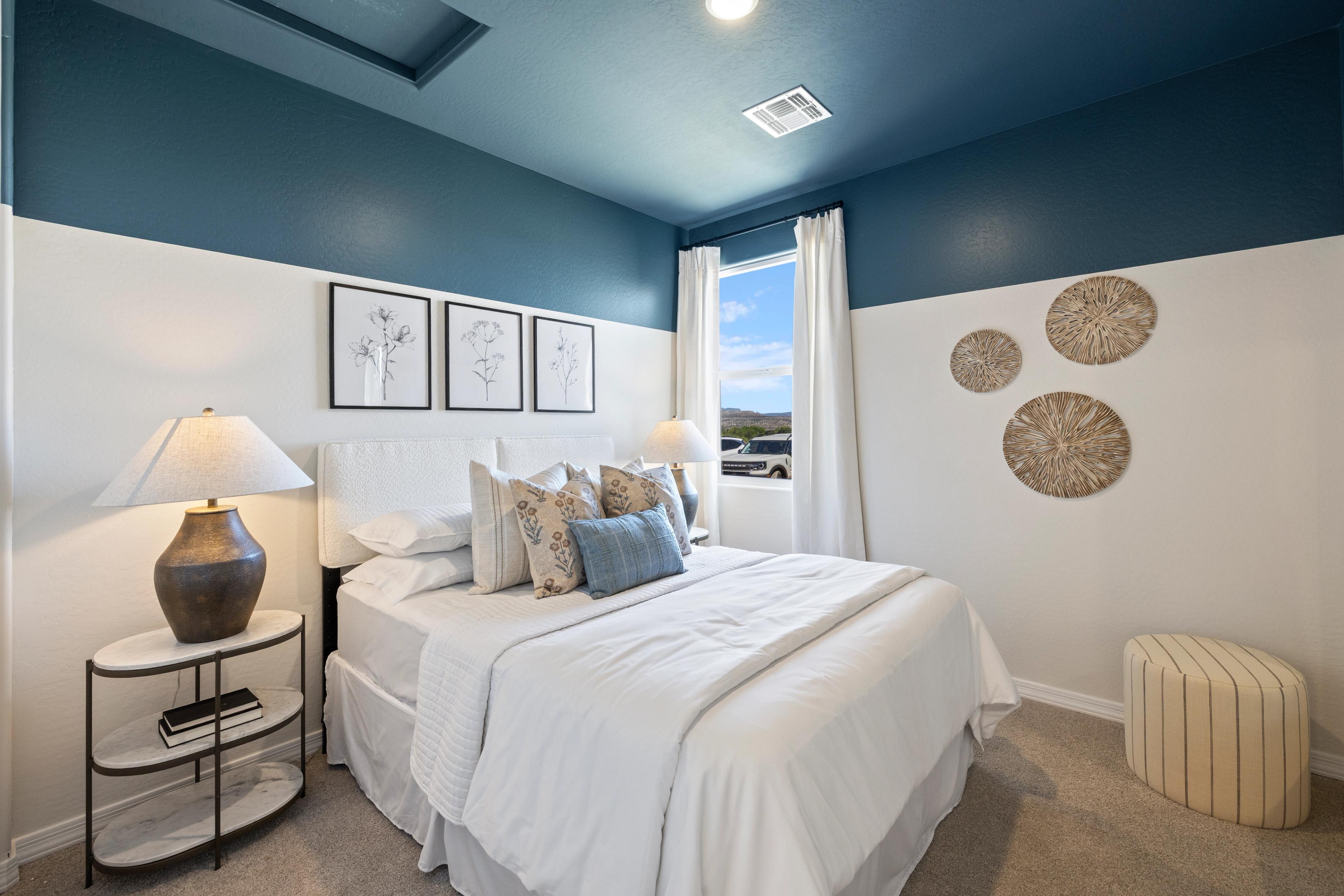 Spacious master bedroom at Vineyards at Cottonwood in Cottonwood AZ with navy accent wall, king bed, woven wall art, and botanical prints