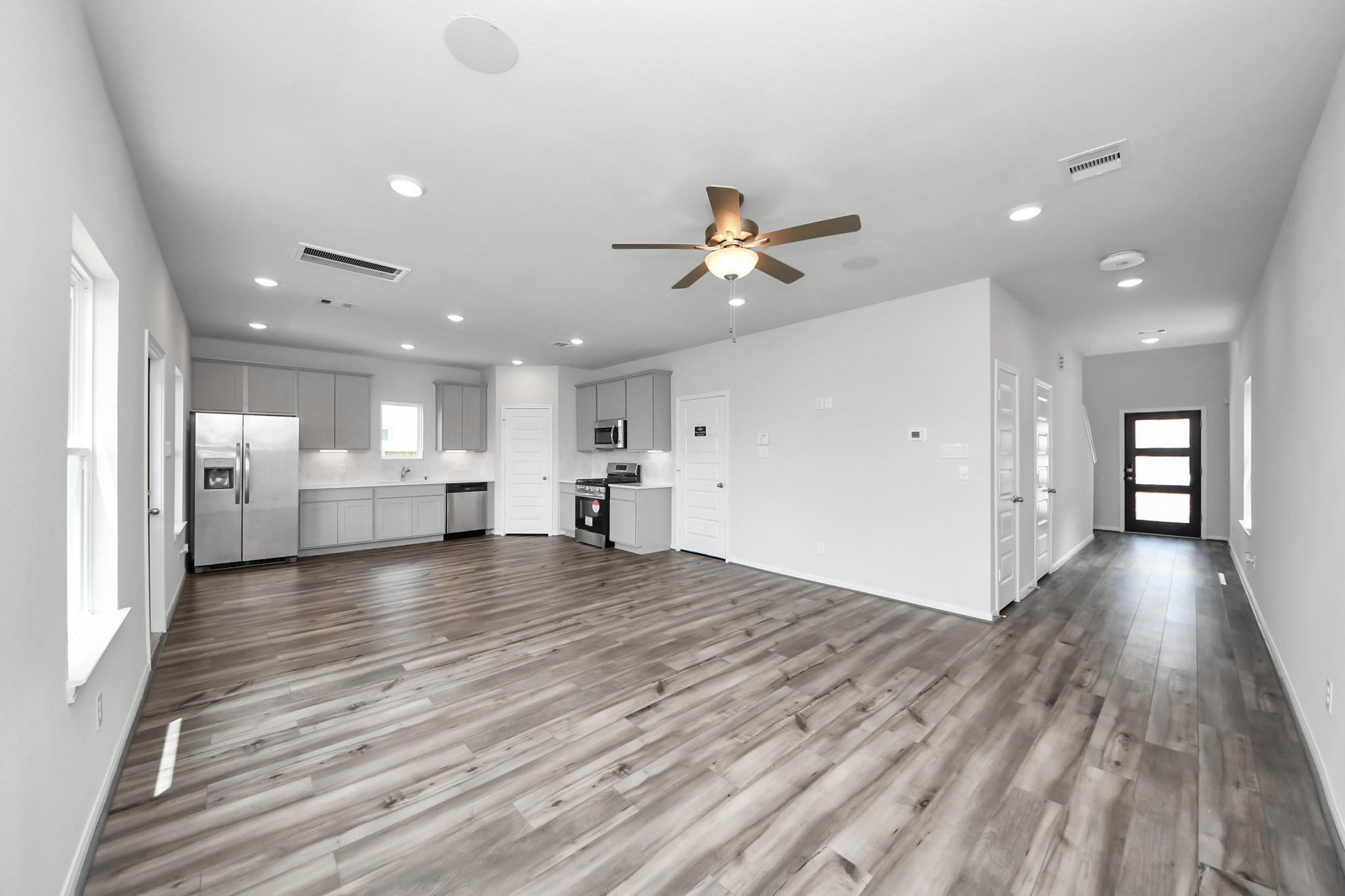Open-concept kitchen and living area with luxury vinyl plank flooring in Davidson Homes Trinity F plan, Splendora, TX