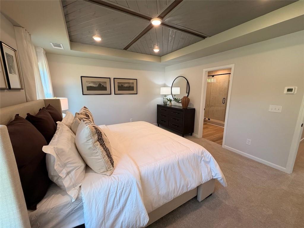 Elegant owner's suite with coffered wood-plank ceiling, plush king bed, and dark dresser in Davidson Homes Pinecrest J, Cartersville GA