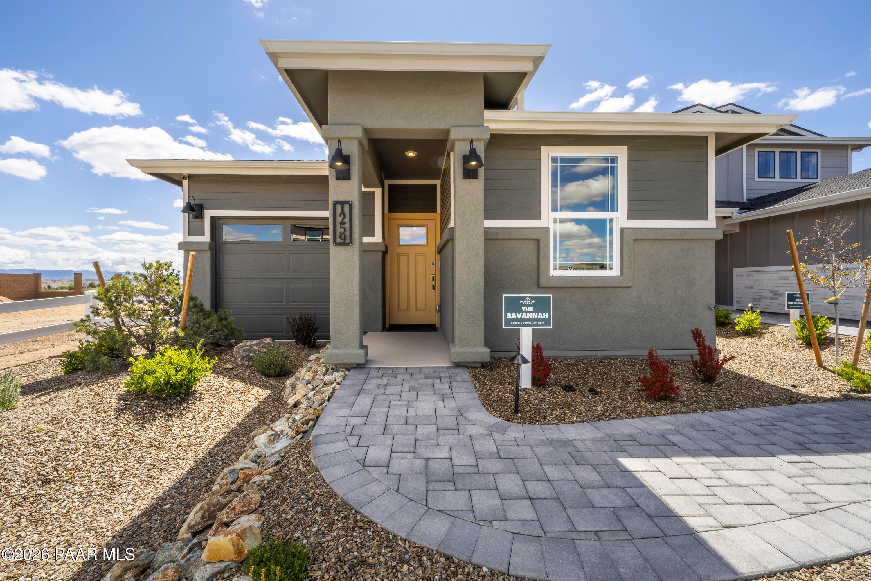 Front exterior of The Savannah A by Davidson Homes with covered porch, paver walkway, and desert landscaping in Prescott, Arizona