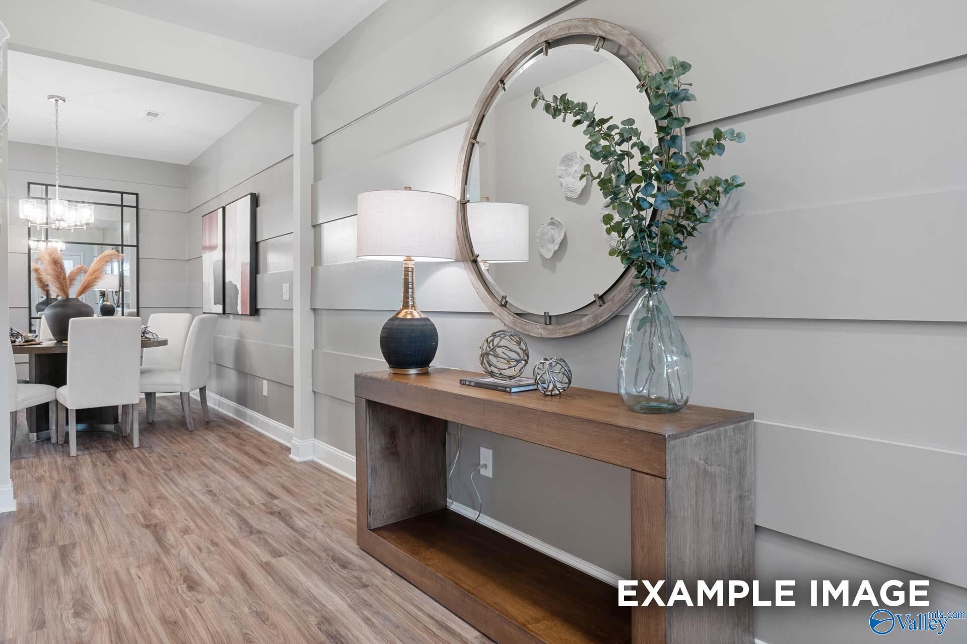 Elegant entryway with rustic console table, round wood mirror, and accent lamp in Davidson Homes The Camilla C, Hartselle, Alabama