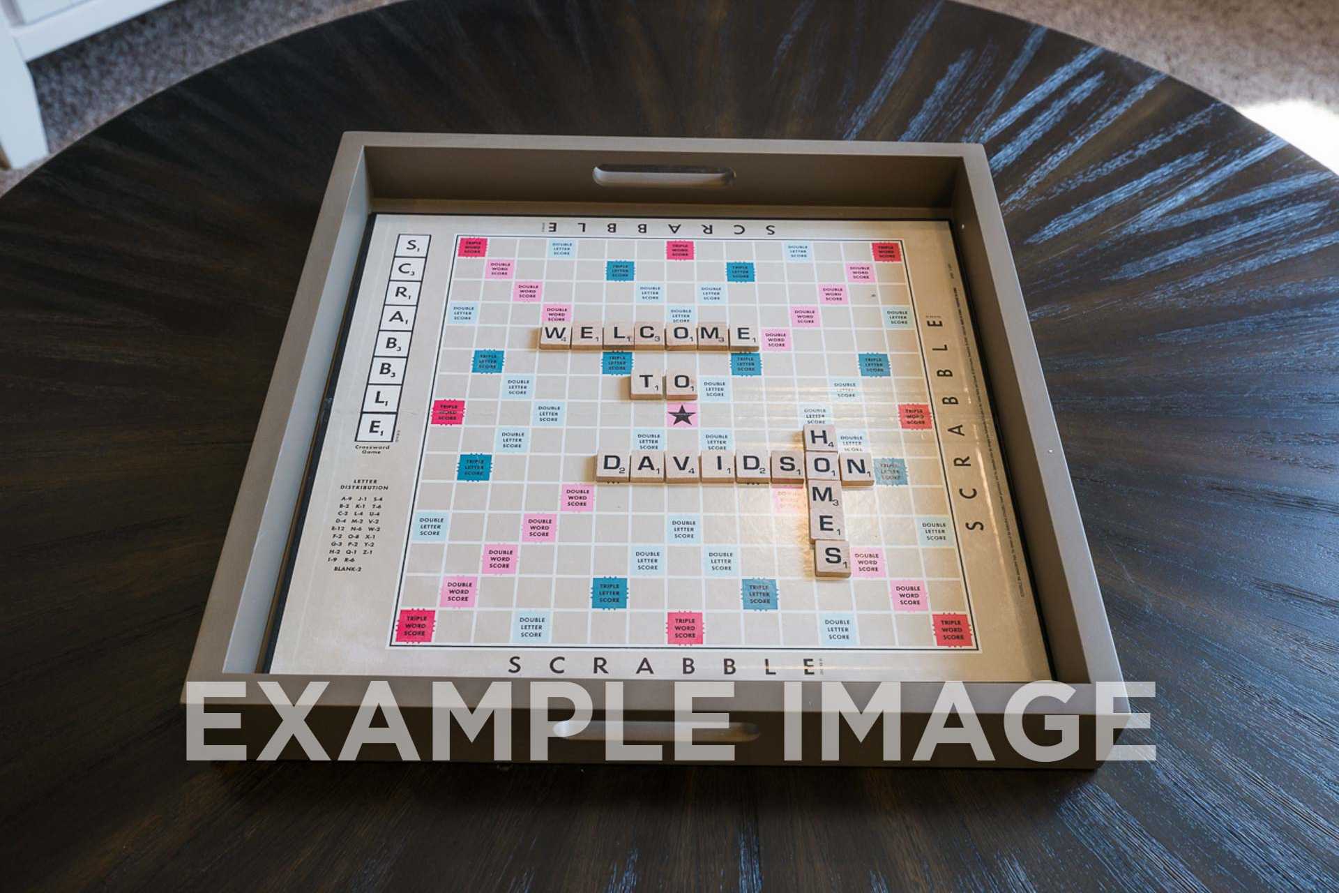 Scrabble board in gray tray on wooden table spelling "Welcome to Davidson Homes" with colorful letter tiles