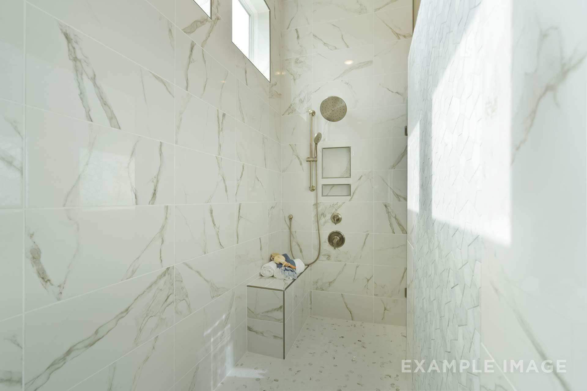 Luxurious walk-in shower in The Seaside master bath featuring white marble tiles, rain showerhead, and glass enclosure