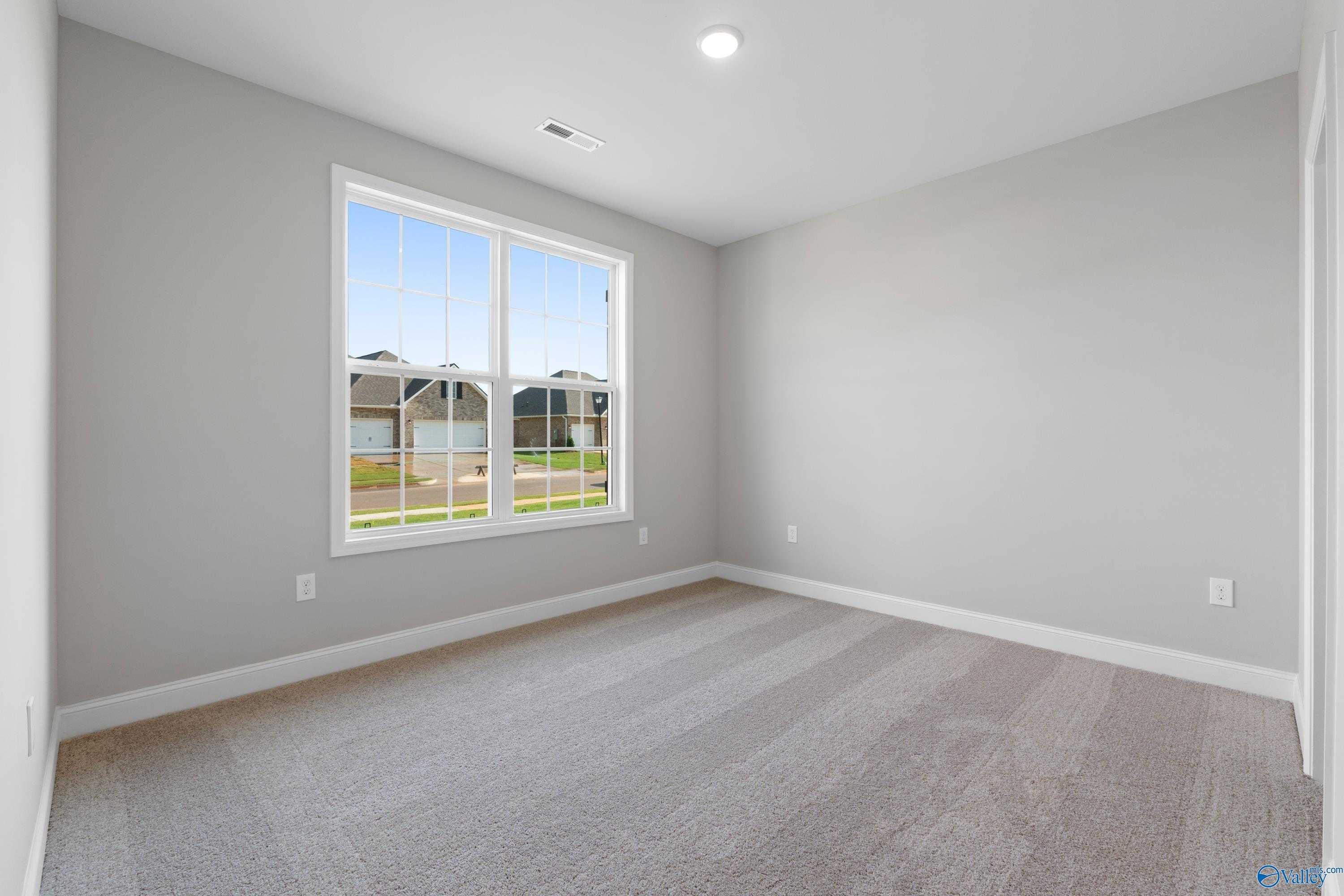 Bright bedroom with large window overlooking grassy backyard in Davidson Homes The Rockford, Toney, Alabama