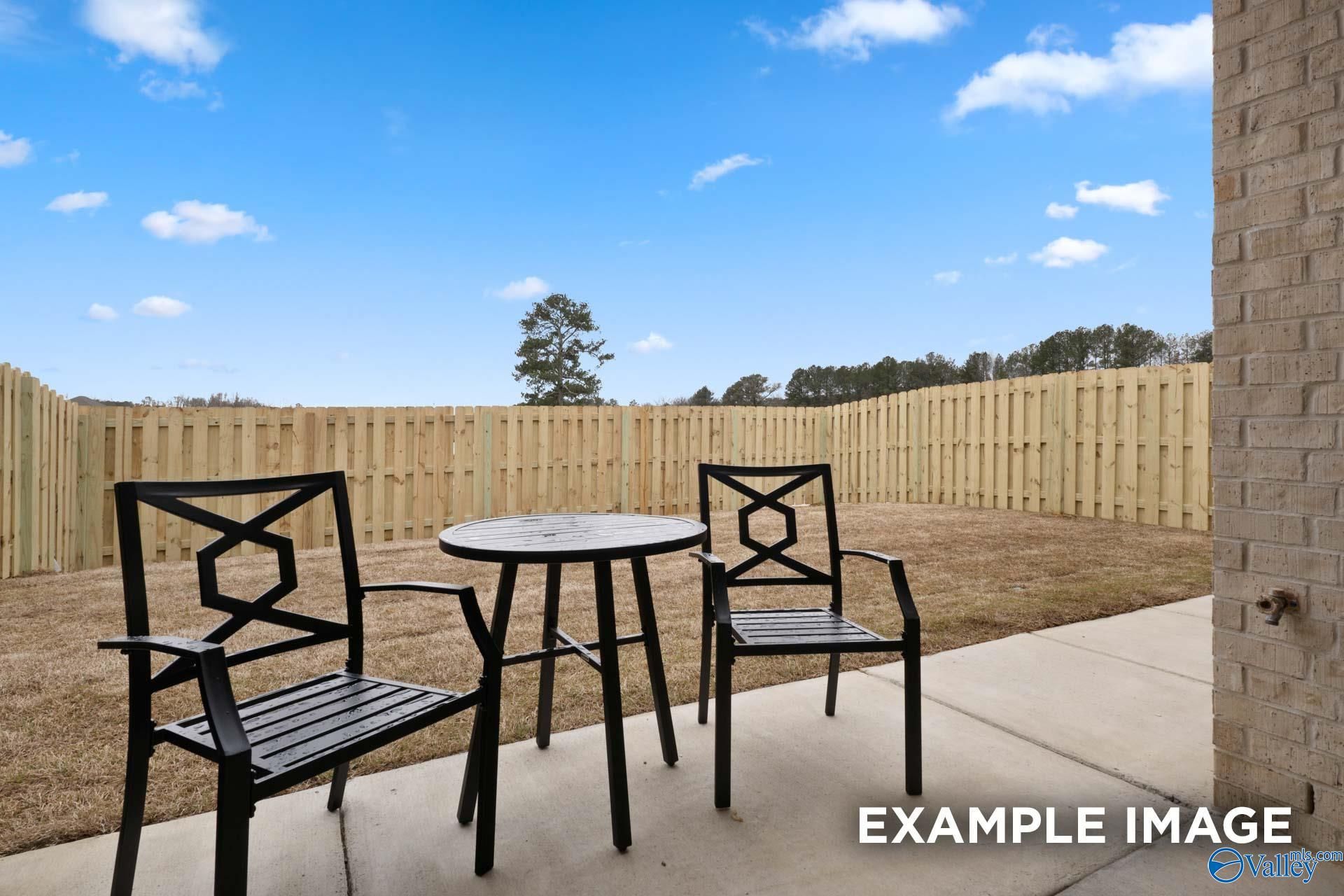 Concrete patio with black metal bistro set in fenced backyard of Davidson Homes Camilla C plan, The Retreat at Cain Park, Hartselle
