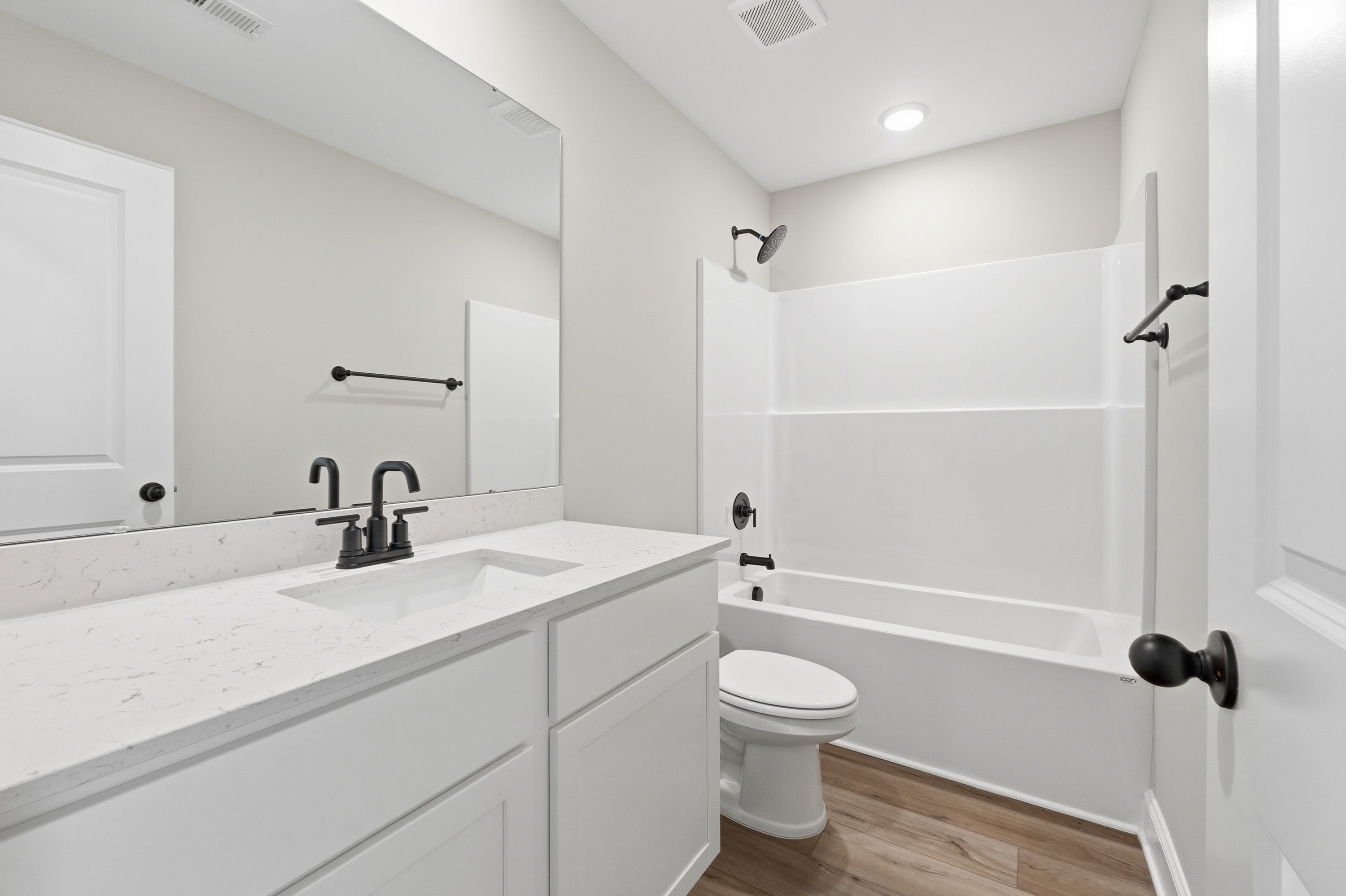 Spacious master bathroom in The Daphne V featuring white subway tile shower, soaking tub, quartz vanity, and matte black fixtures
