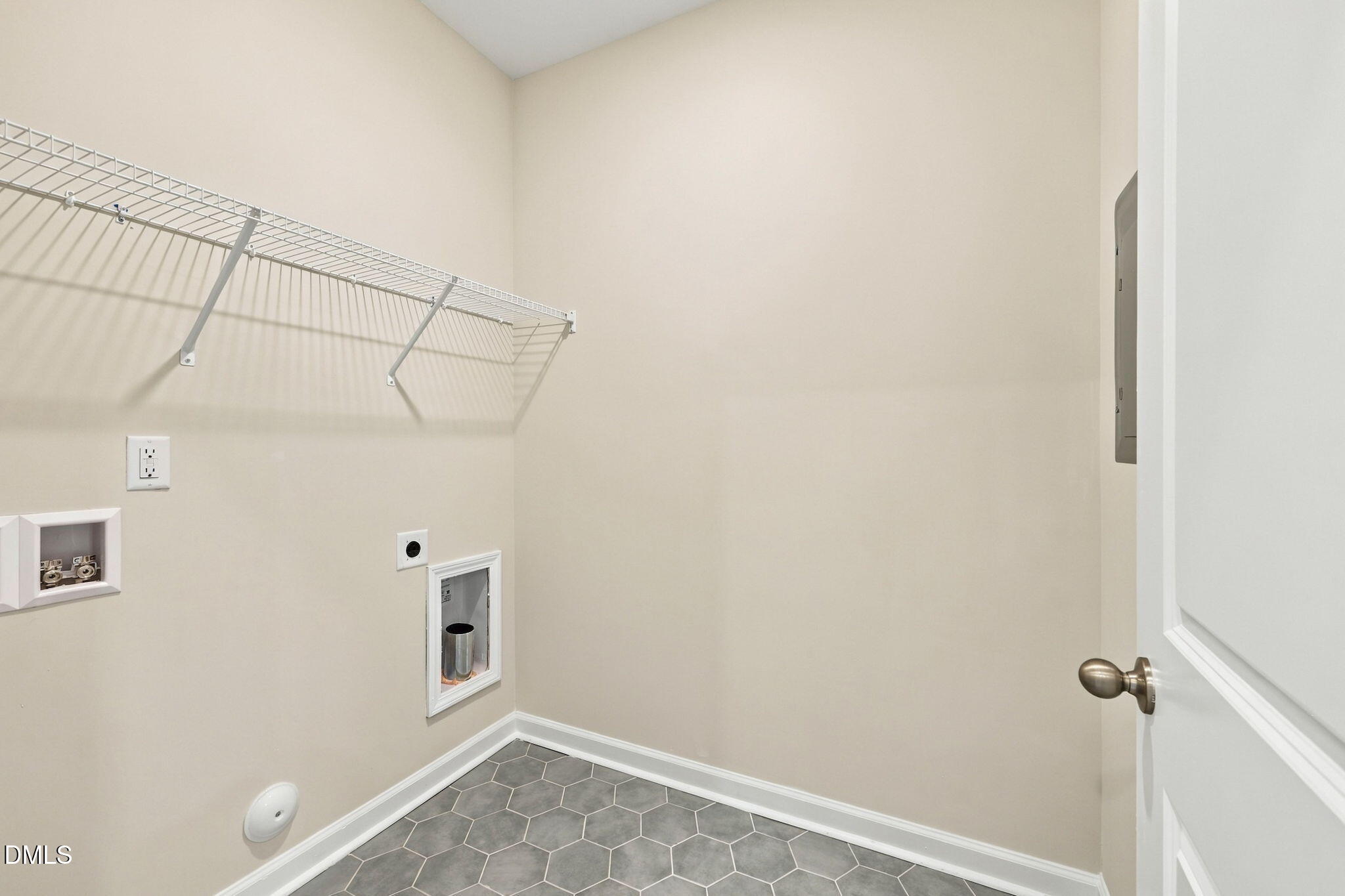 Laundry room with wire shelving, washer/dryer hookups, and hexagon tile floor in Davidson Homes The Alexander B, Knightdale, NC