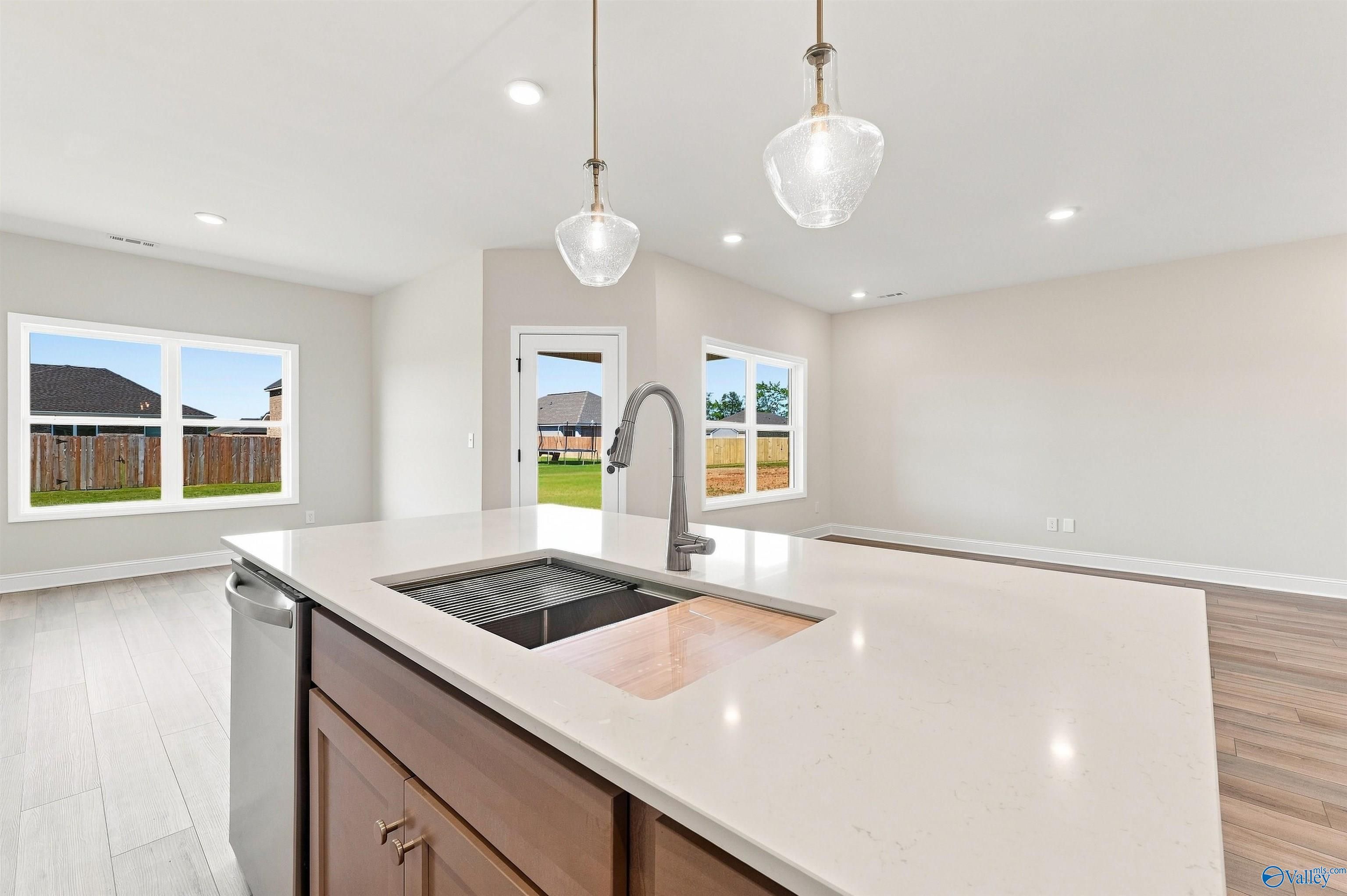 Kitchen island with quartz countertop, sink, and pendant lights in open-concept Davidson Homes Everett B plan, Toney, Alabama