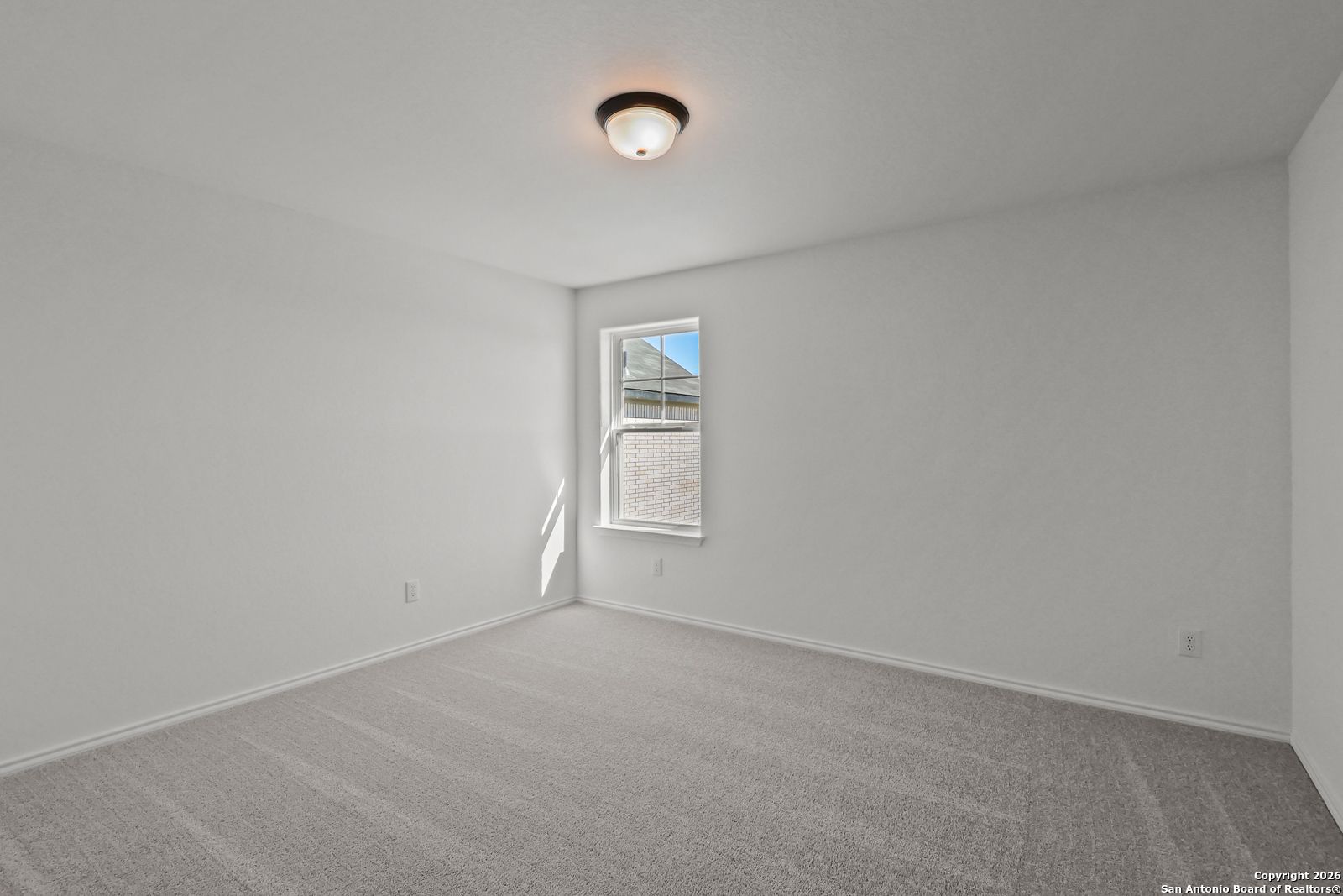 Empty bedroom with gray carpet, large window, and ceiling light in 4-bedroom Davidson Homes The Douglas E, Comanche Ridge, San Antonio