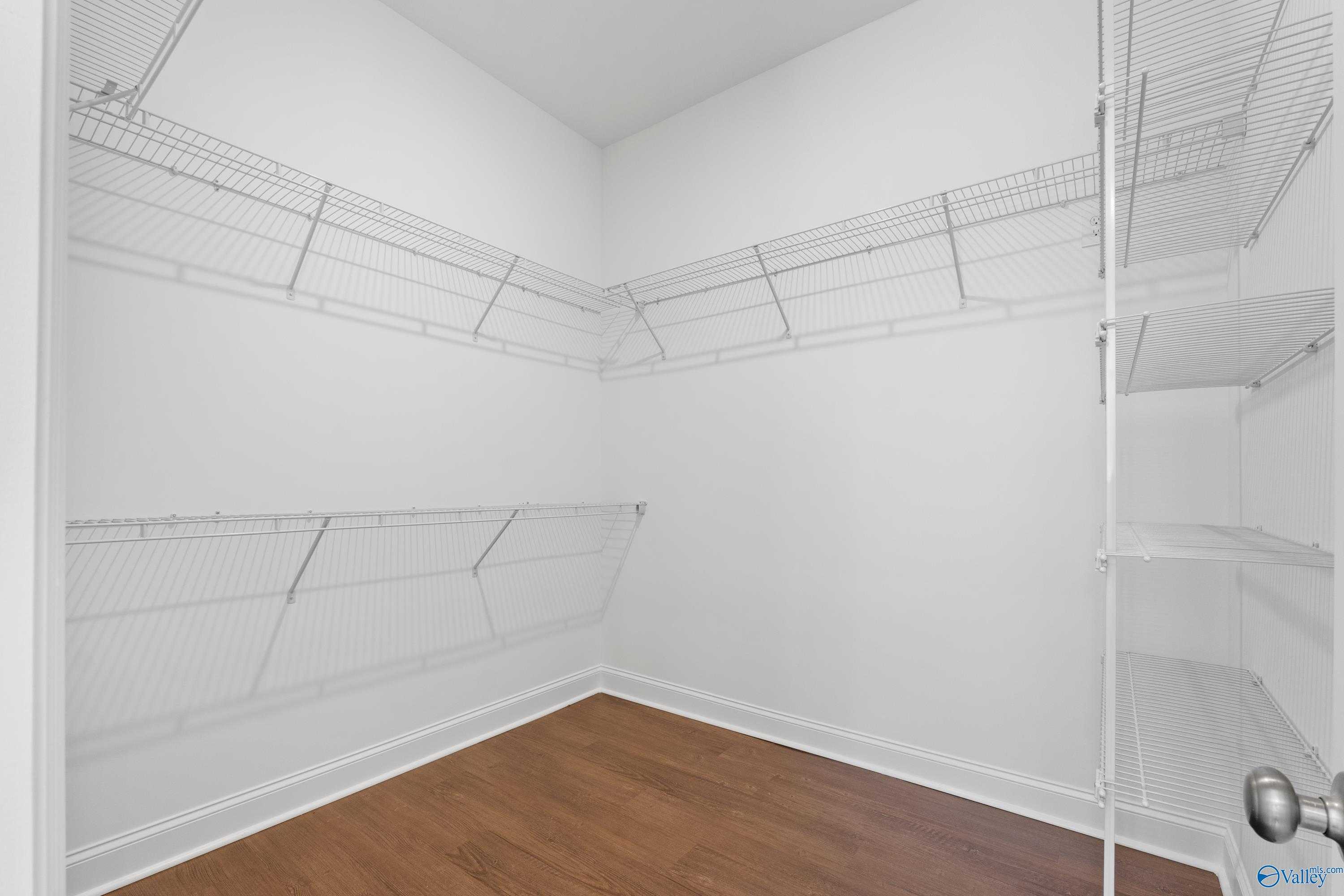 Spacious walk-in closet with wire shelving and hardwood floors in The Haven master suite by Evermore Homes, Owens Cross Roads, Alabama