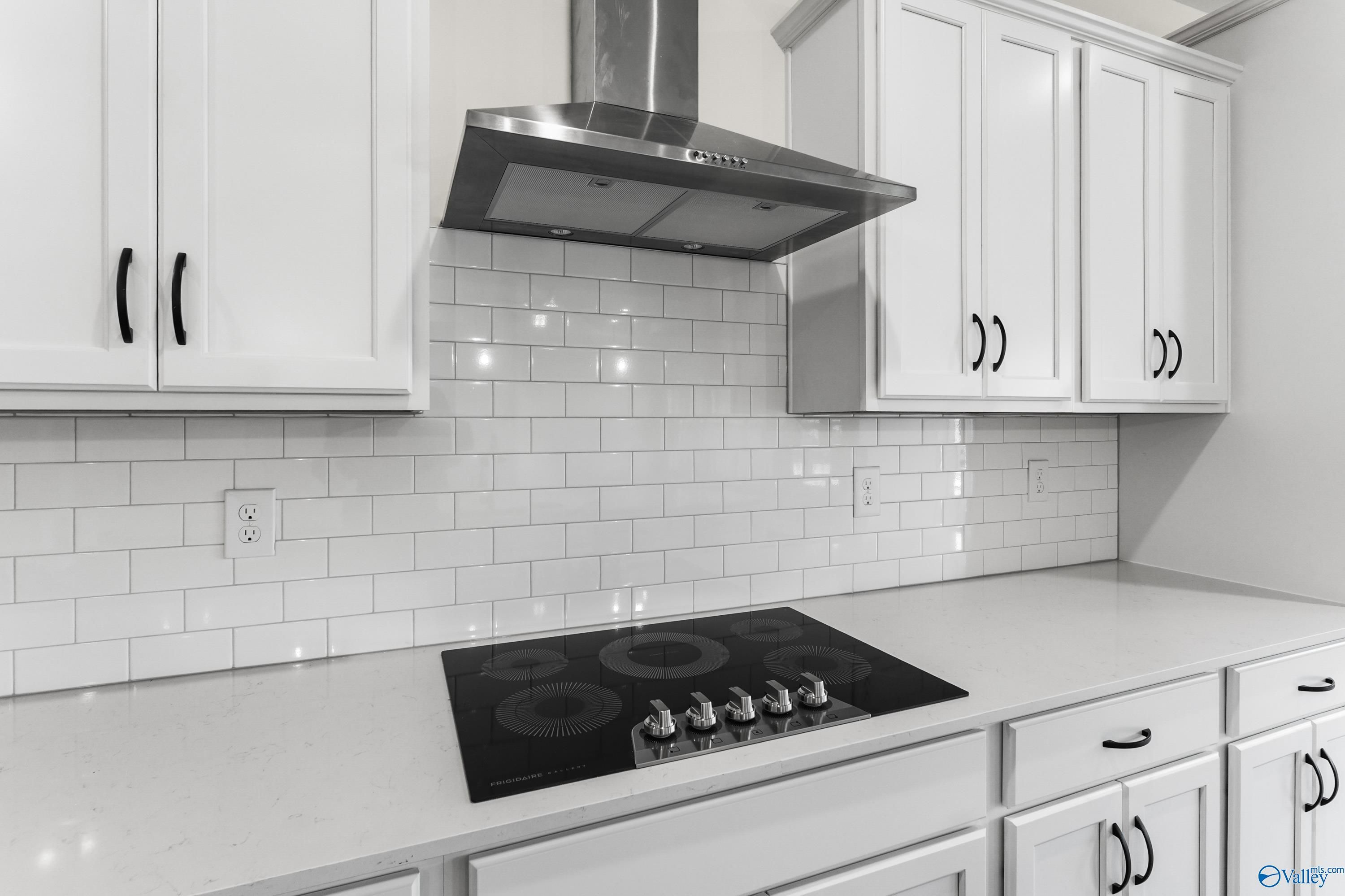 Modern kitchen featuring white shaker cabinets, subway tile backsplash, stainless range hood, and gas cooktop in The Finleigh by Davidson Homes, Harvest, AL