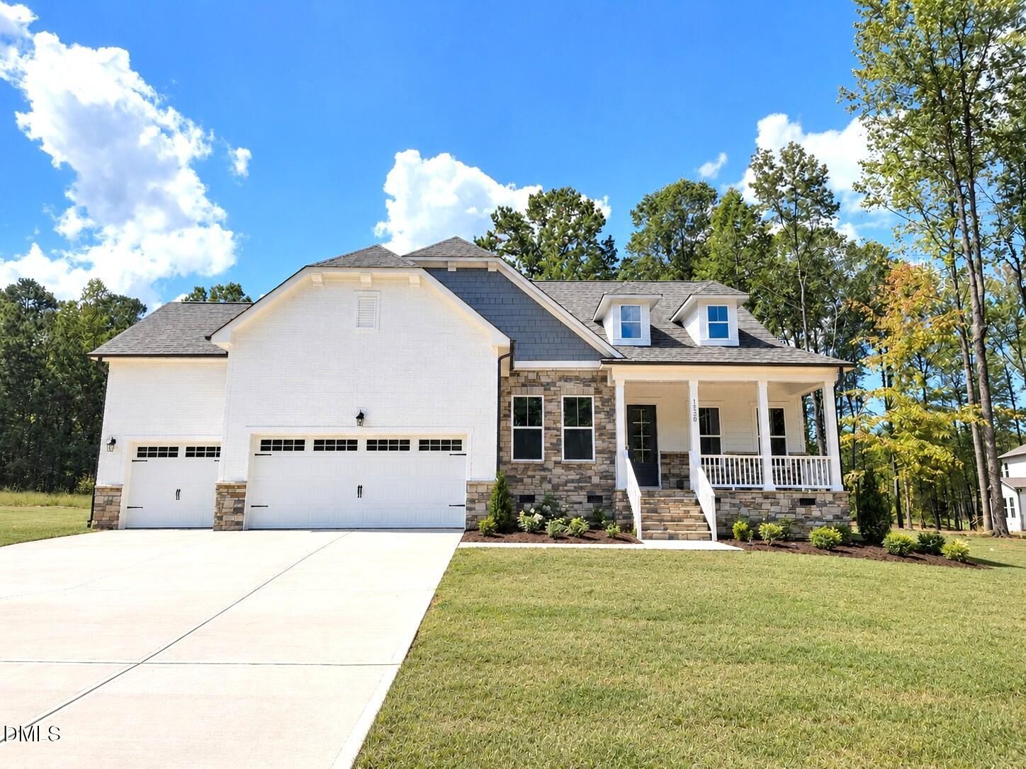 White brick and stone exterior with covered front porch and 3-car garage at The Magnolia II B in Rockport, Wake Forest, NC