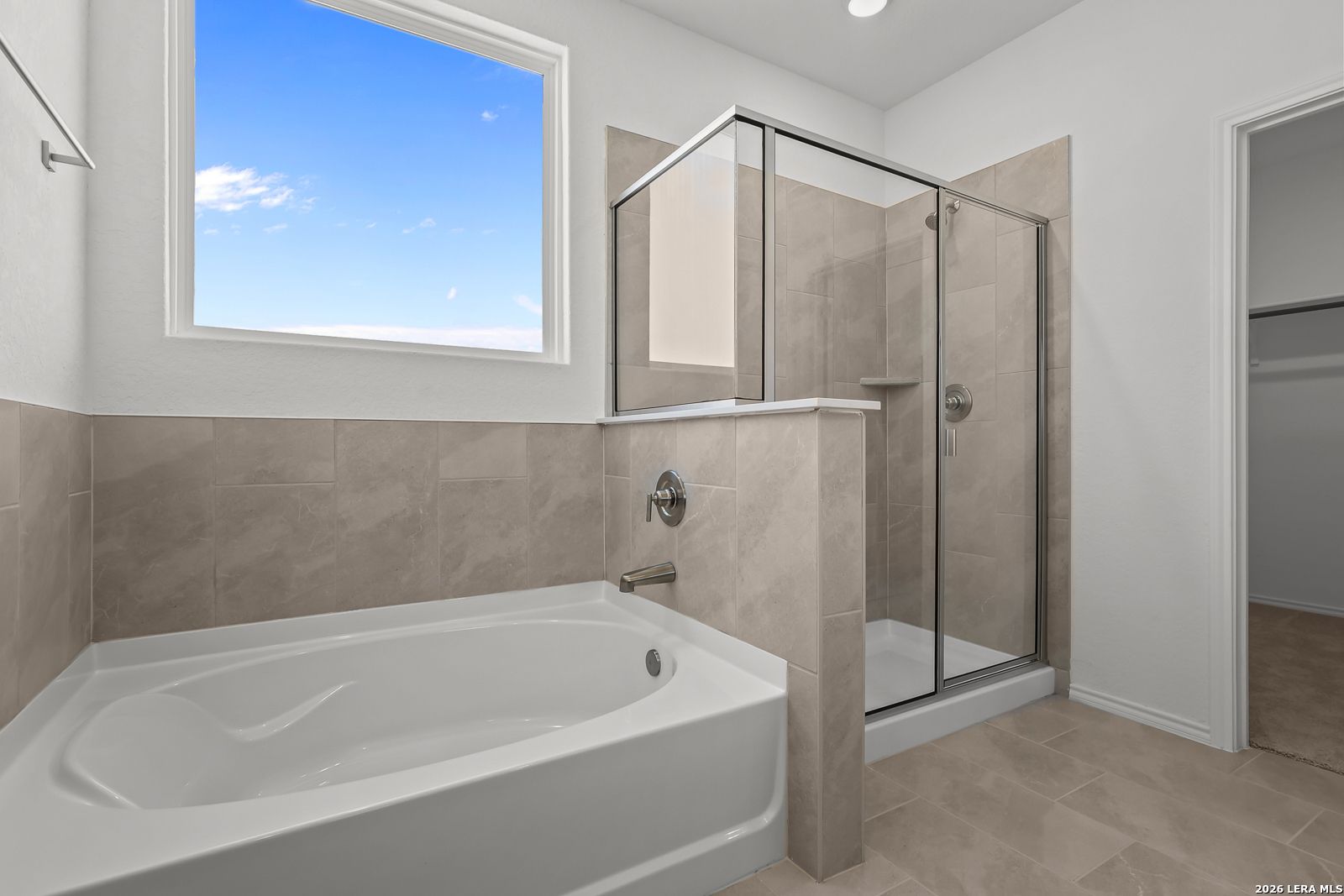 Elegant master bathroom with freestanding tub, glass walk-in shower, beige tiles, and large sky-view window in Davidson Homes Sequoia B, San Antonio