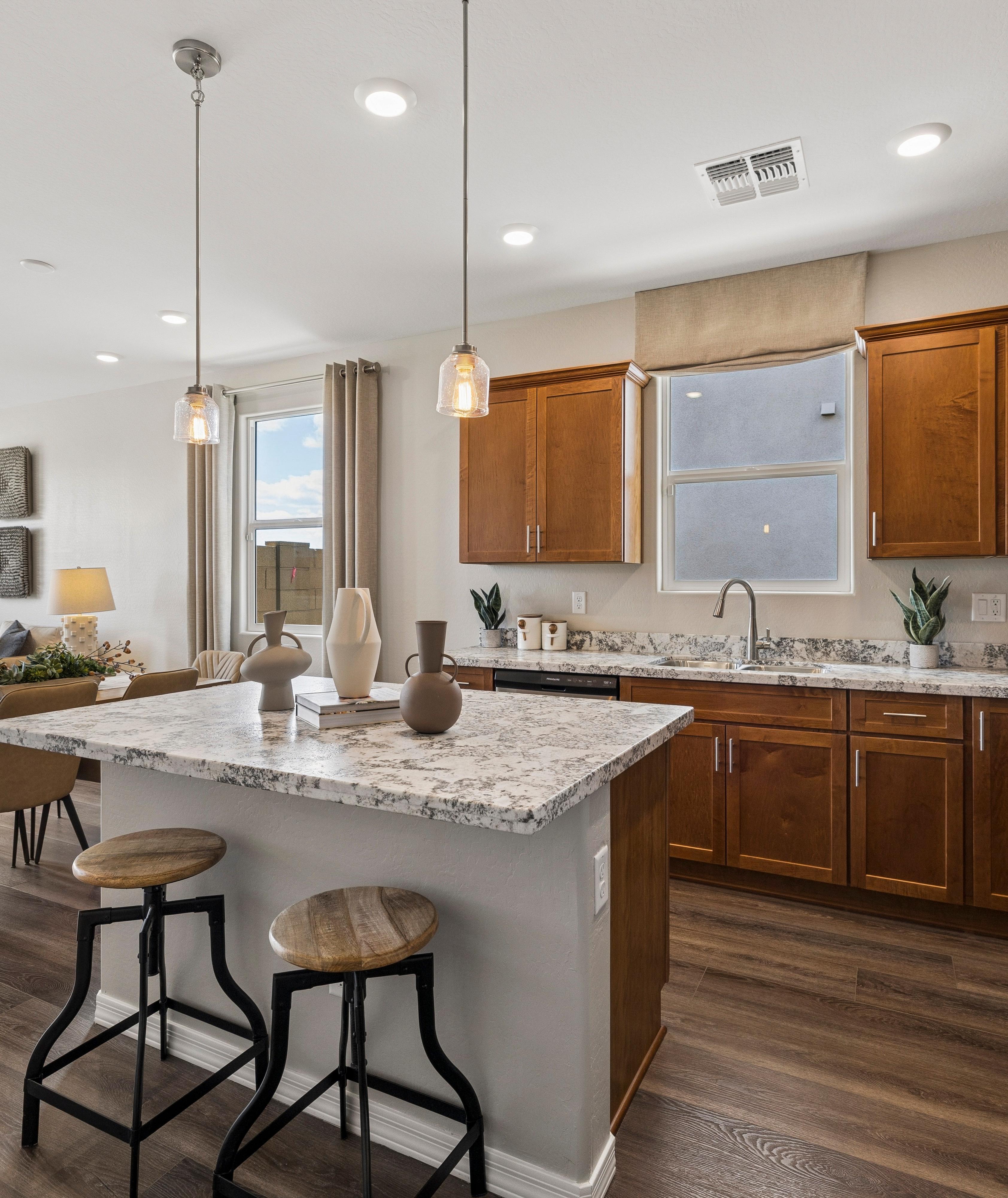 Spacious white kitchen at Senator Cottages in Prescott AZ with quartz island, bar stools, pendant lights, and stainless appliances