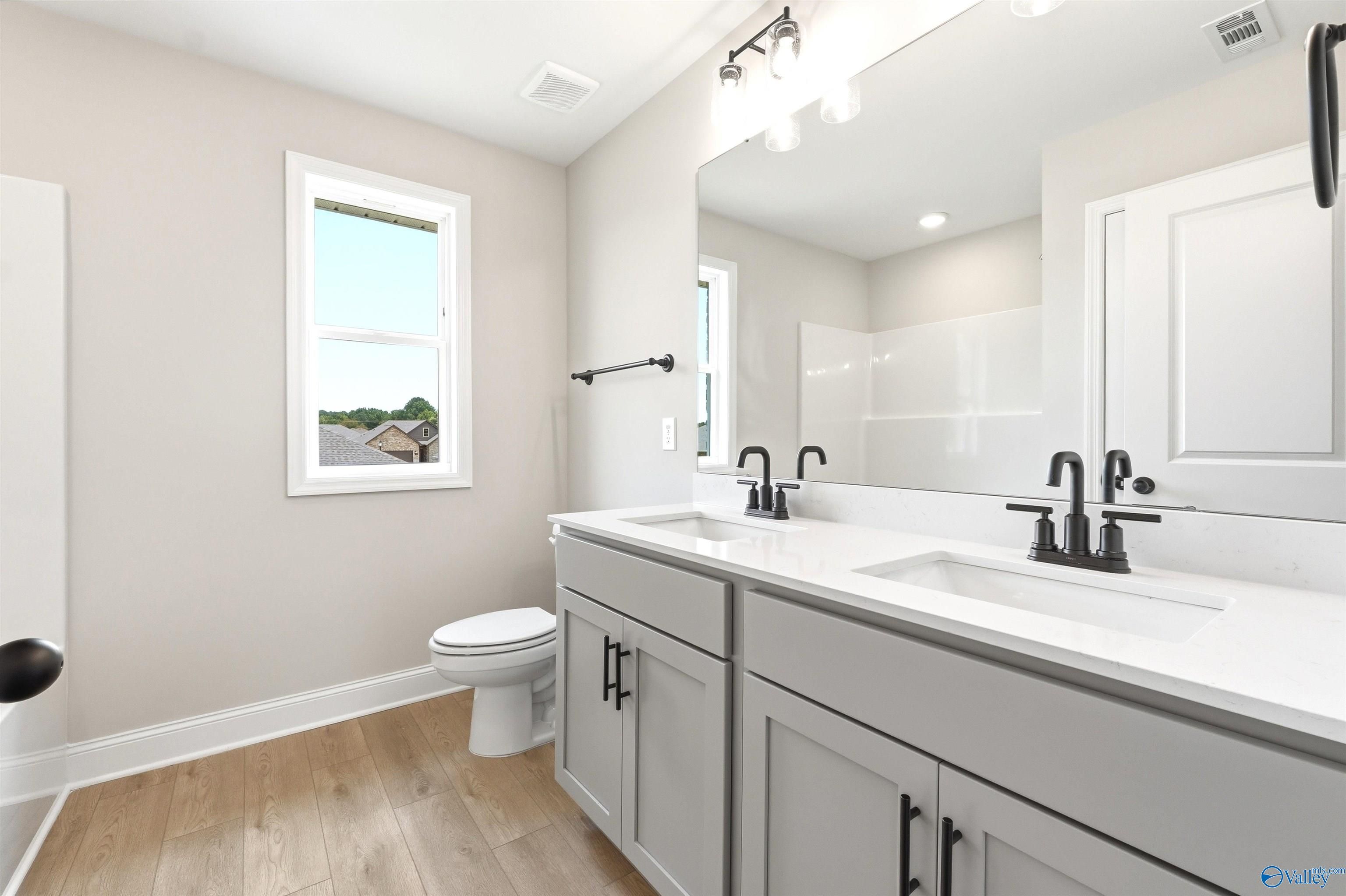Modern bathroom with double vanity, quartz countertops, and matte black fixtures in The Shelby A home at Wood Trail.