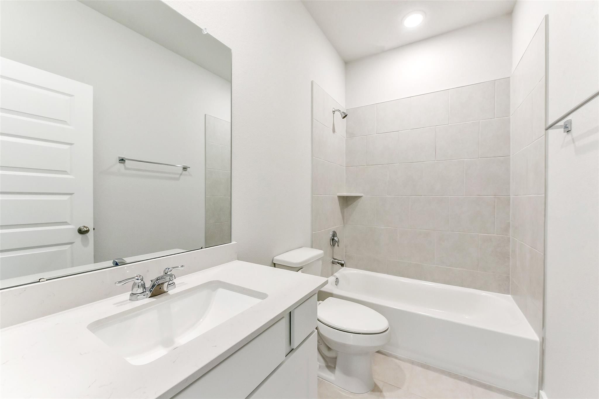 Bright guest bathroom with white vanity, tub-shower combo, and toilet in Davidson Homes The Costa B, Dayton, Texas