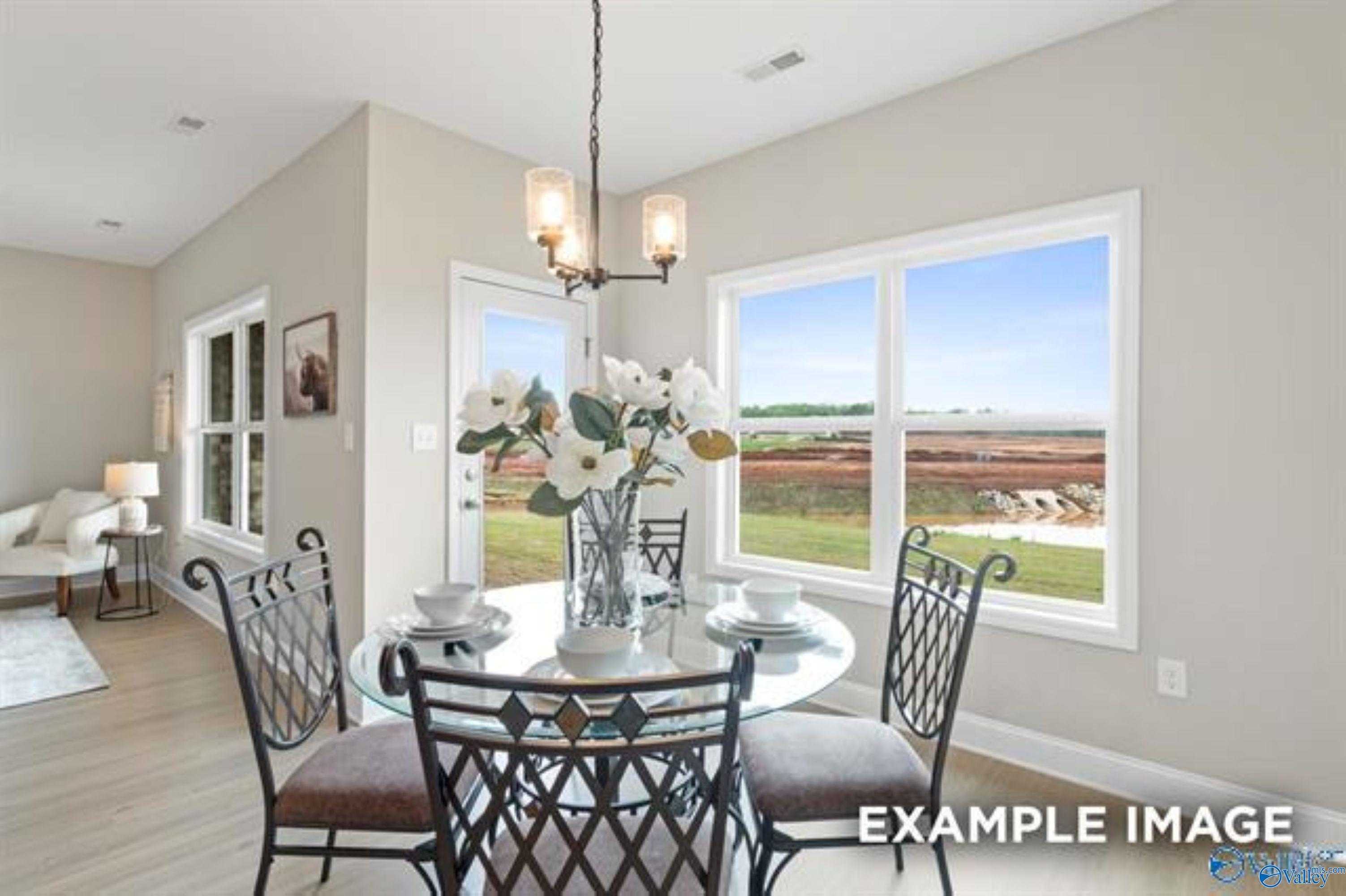 Elegant dining room with round glass table, floral centerpiece, and countryside views through large windows in The Asheville home, Ramsay Cove, Alabama