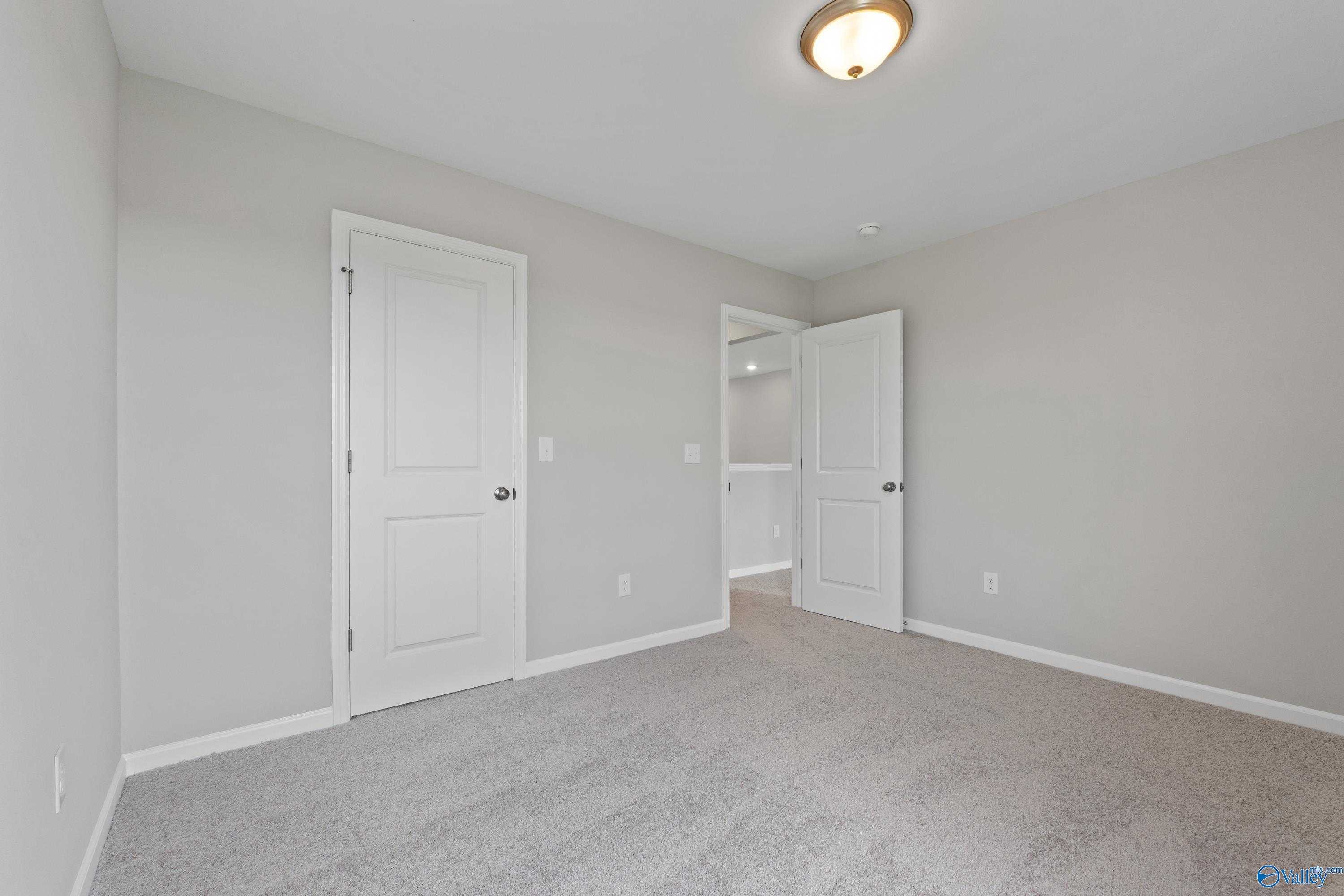 Cozy secondary bedroom with light gray walls, beige carpet, white doors to closet in Davidson Homes The Dorado, Athens AL