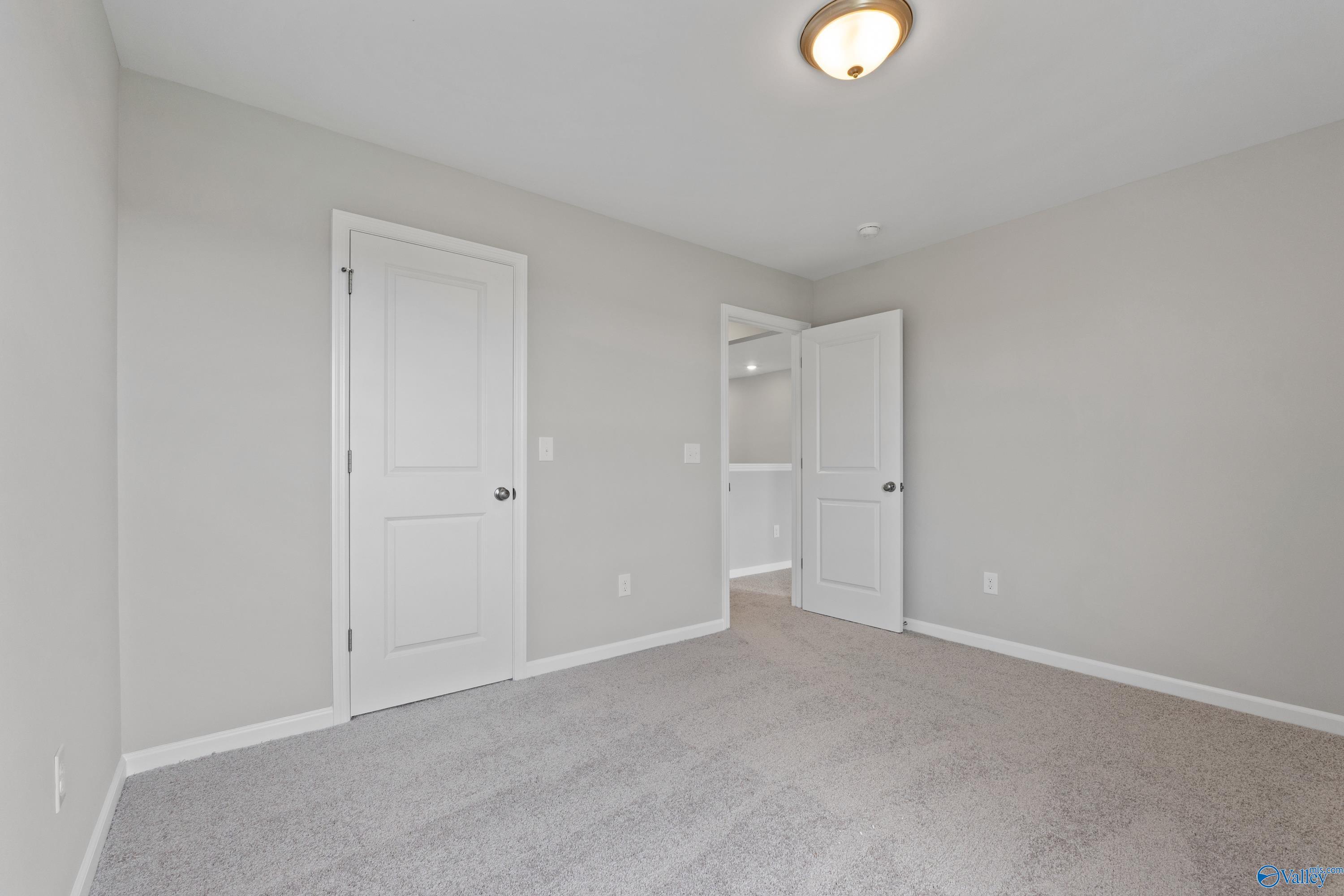 Spacious secondary bedroom with light gray walls, white doors to en-suite bath, plush carpet in Davidson Homes The Dorado, Athens AL