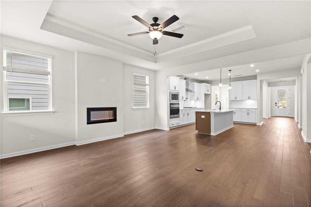 Open-concept great room featuring modern white kitchen island, gas fireplace, hardwood floors in Davidson Homes The Glenwood C, Loganville, GA