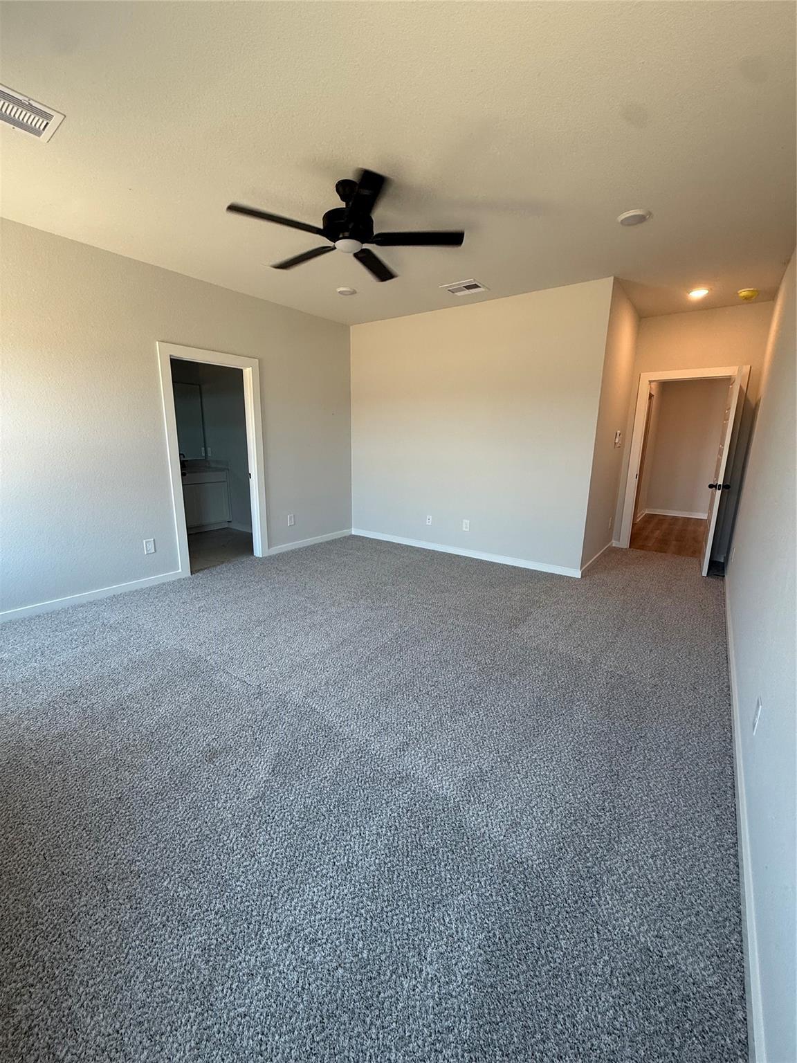 Spacious master bedroom with neutral carpet and ceiling fan in The Sorrento E floor plan at Sundance Cove, Crosby, Texas.