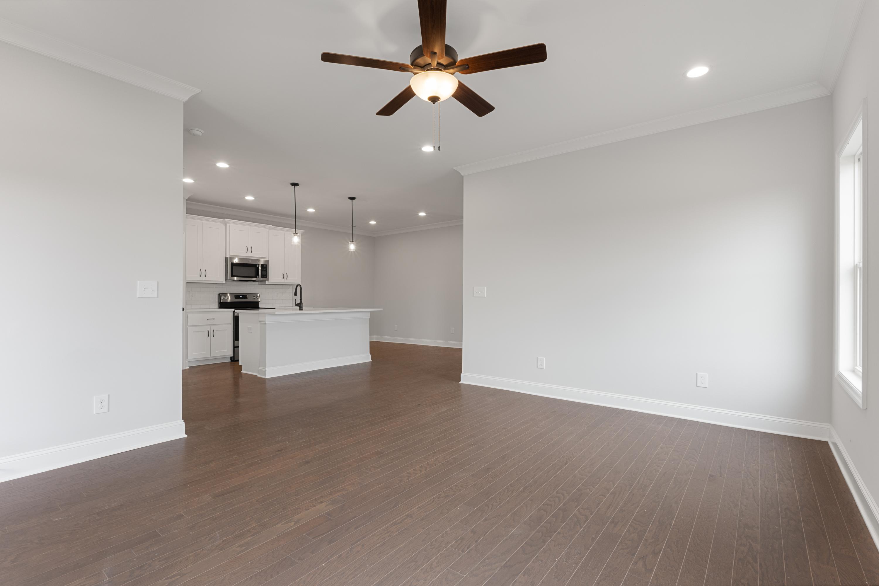 Spacious open-concept kitchen and living area in The Copeland by Davidson Homes, Madison AL, featuring white cabinets, large island, hardwood floors