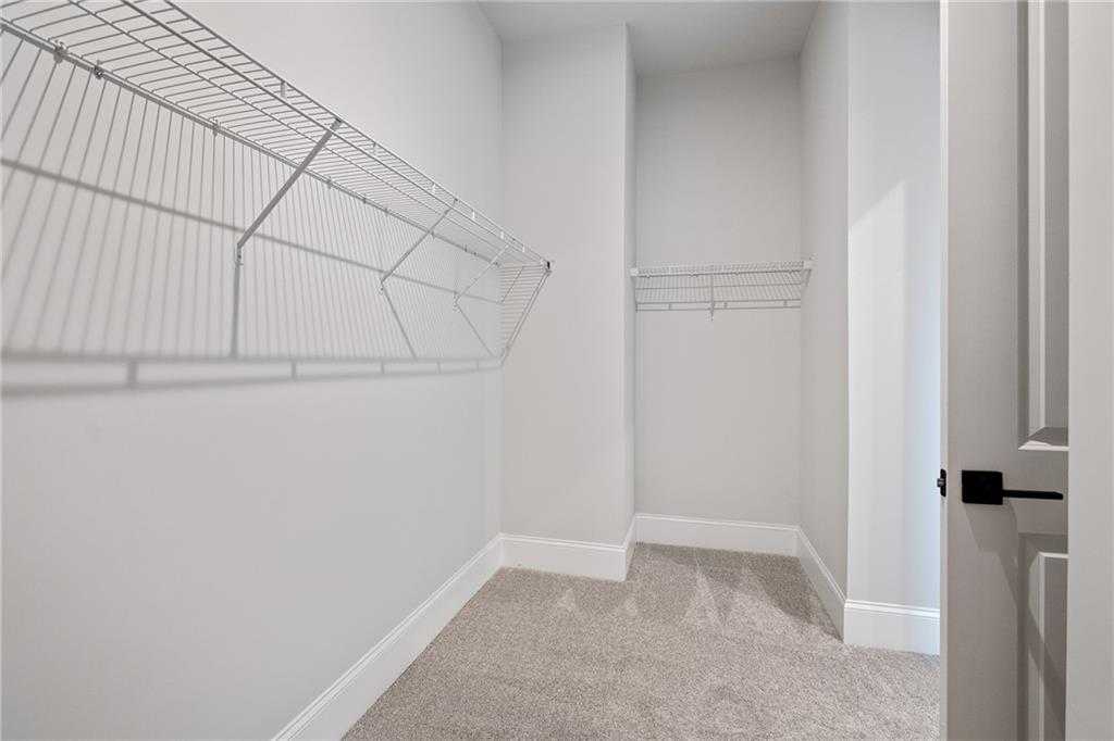 Spacious walk-in closet with wire shelving, hanging rods, and carpeted floor in Davidson Homes The Seaside B, Woodstock, GA