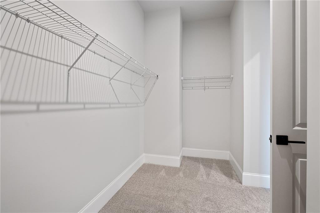 Spacious walk-in closet with wire shelving, hanging rods, and carpeted floor in Davidson Homes The Seaside B, Woodstock, GA