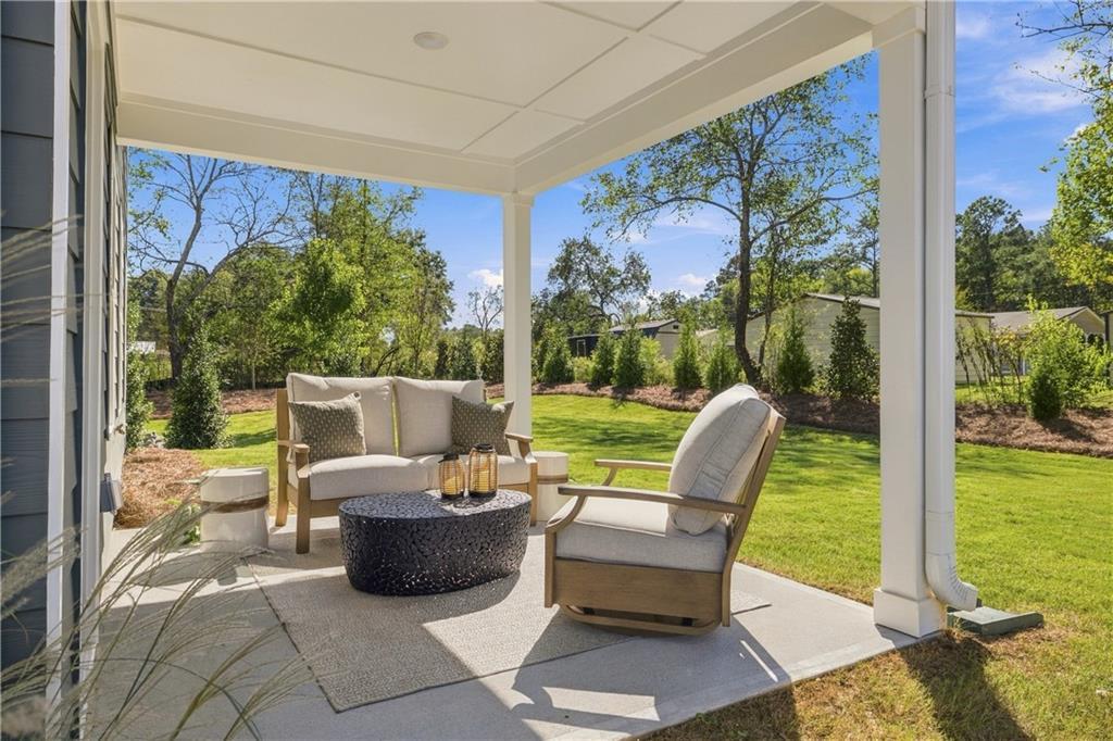 Covered patio with cushioned seating overlooking fenced backyard at Davidson Homes Sinclair B, Greene Farm, Cartersville, Georgia
