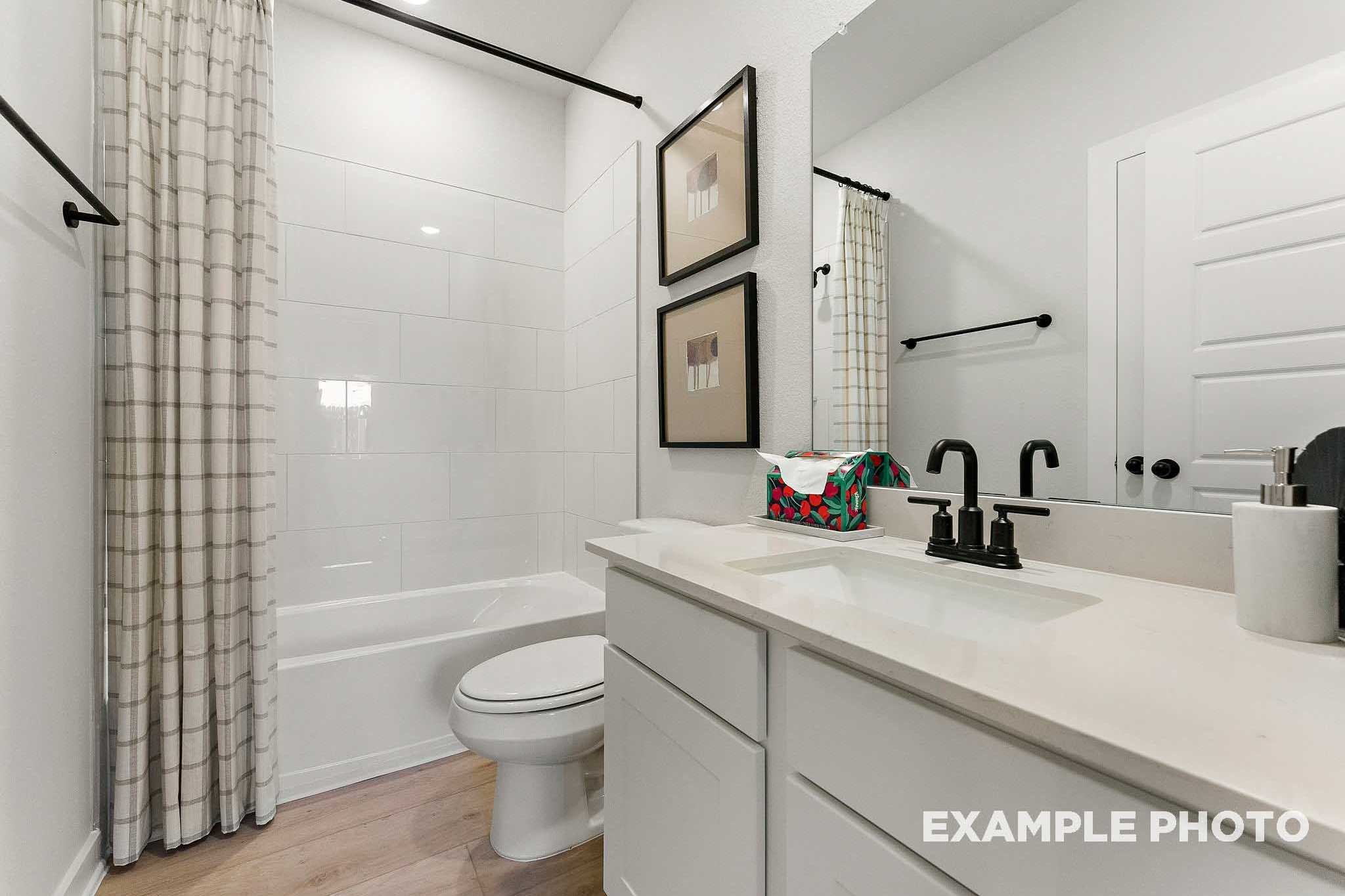 Spacious master bathroom in The Everett E with white subway tile, soaking tub, modern vanity, and framed artwork