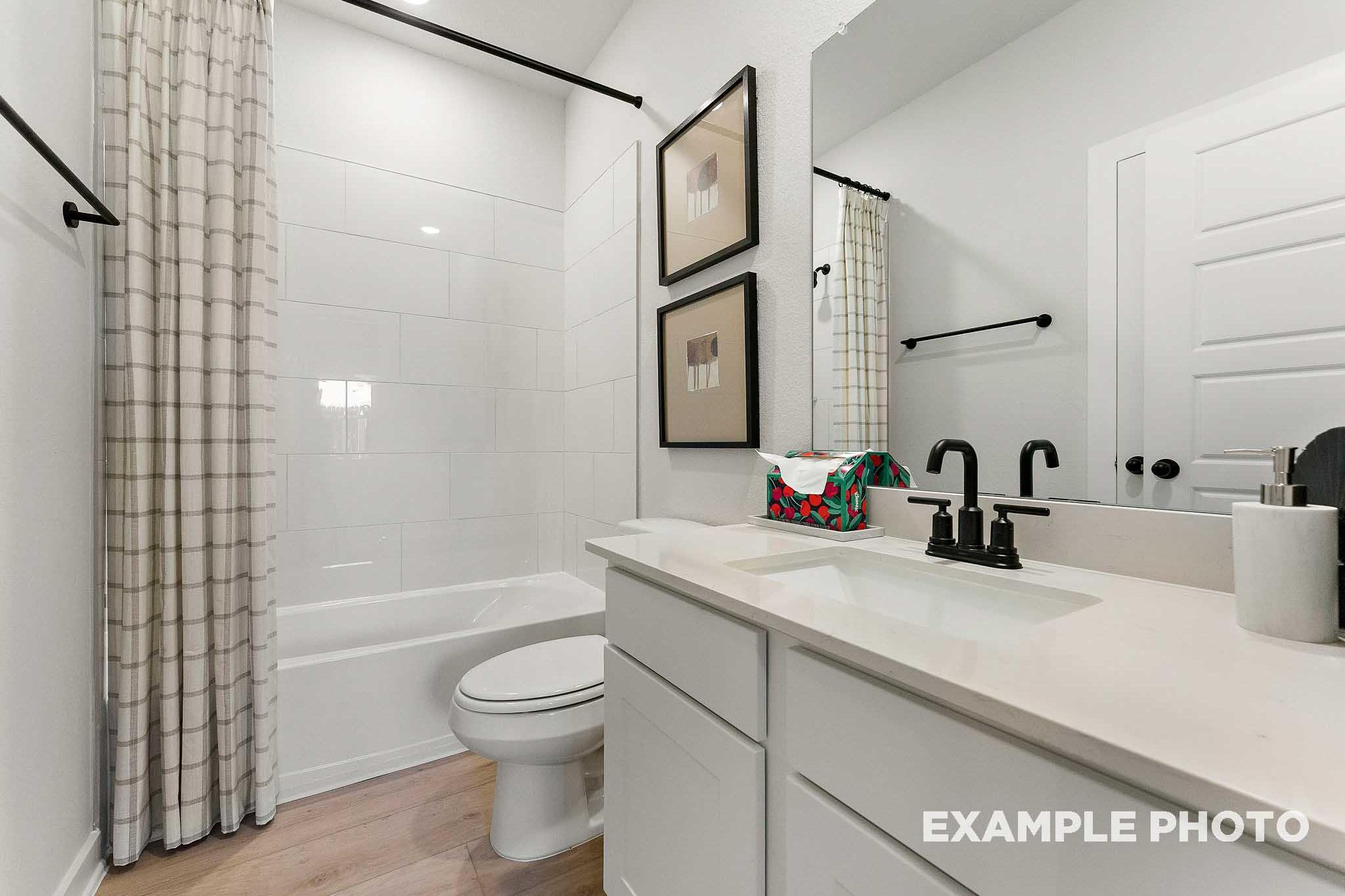 Spacious master bathroom in The Everett E with white subway tile, soaking tub, modern vanity, and framed artwork