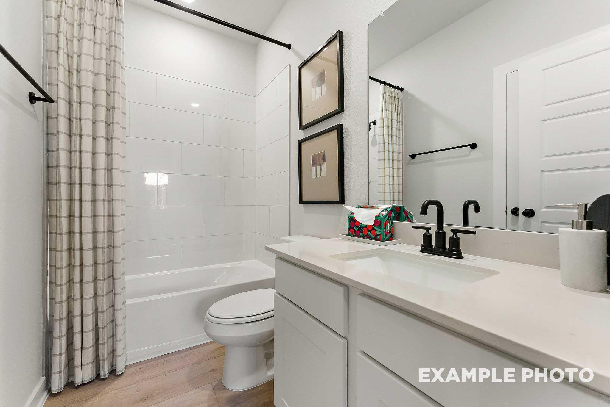 Modern bathroom with subway tile shower and white vanity in The Everett E floor plan at Sundance Cove, Crosby, Texas.