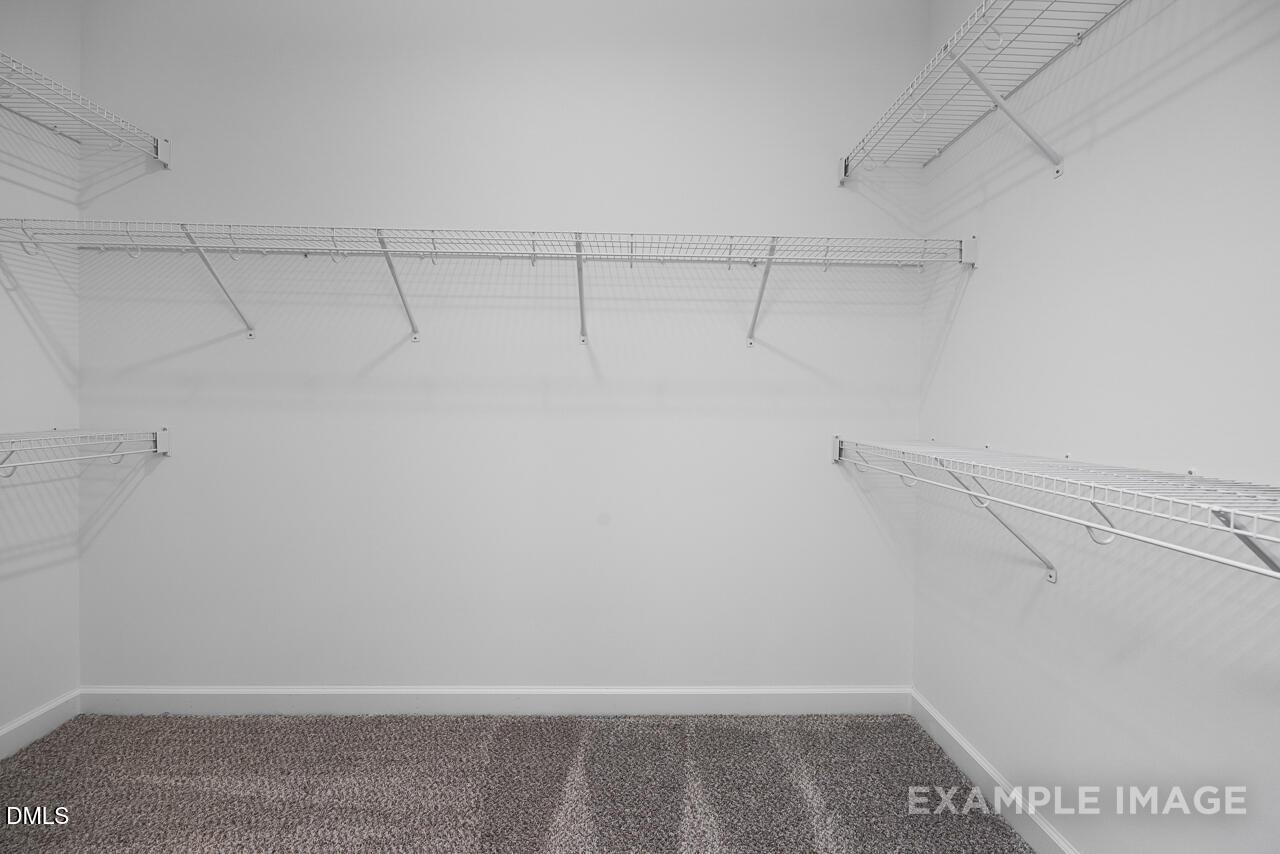 Spacious walk-in closet with wire shelving and carpeted floor in Davidson Homes The Magnolia D, Angier, NC